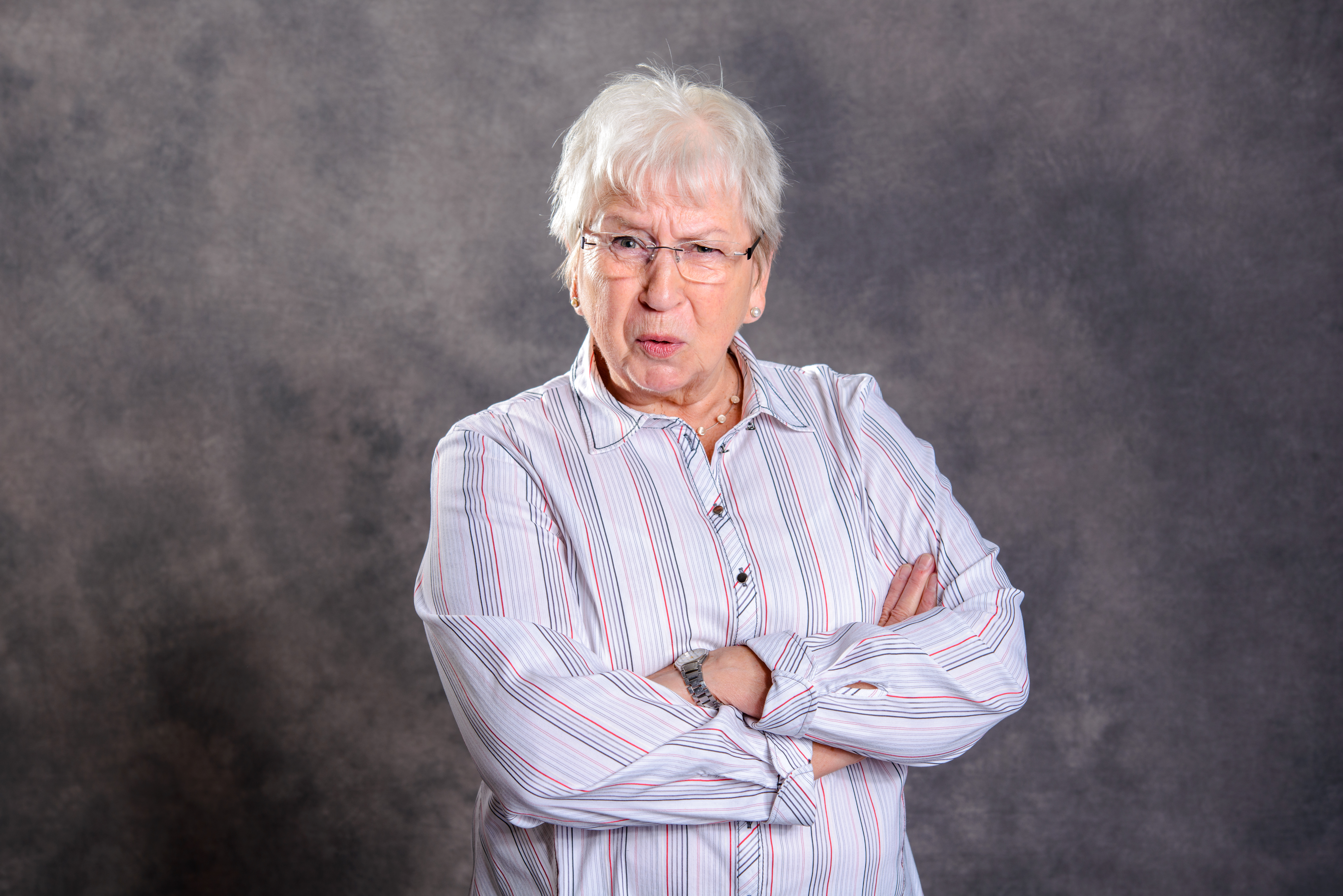 An upset older woman with her arms folded against her chest | Source: Shutterstock