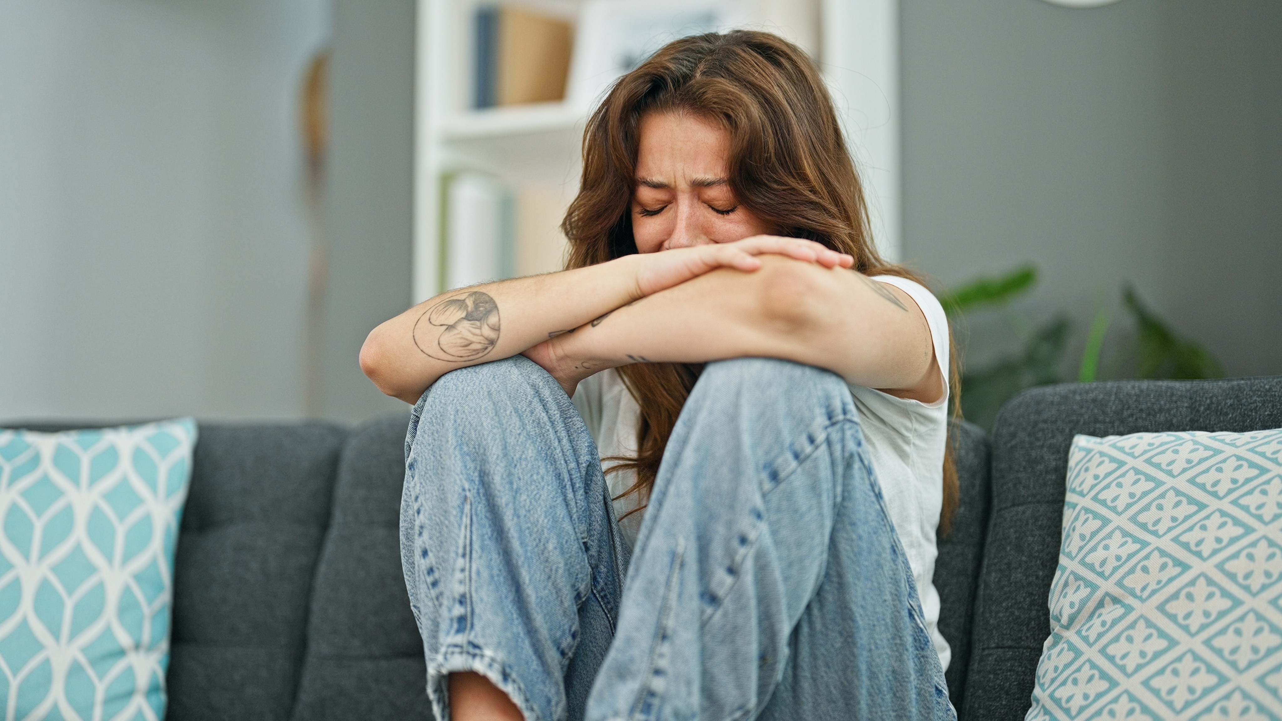 Young beautiful hispanic woman sitting on the sofa crying at home. | Source: Shutterstock