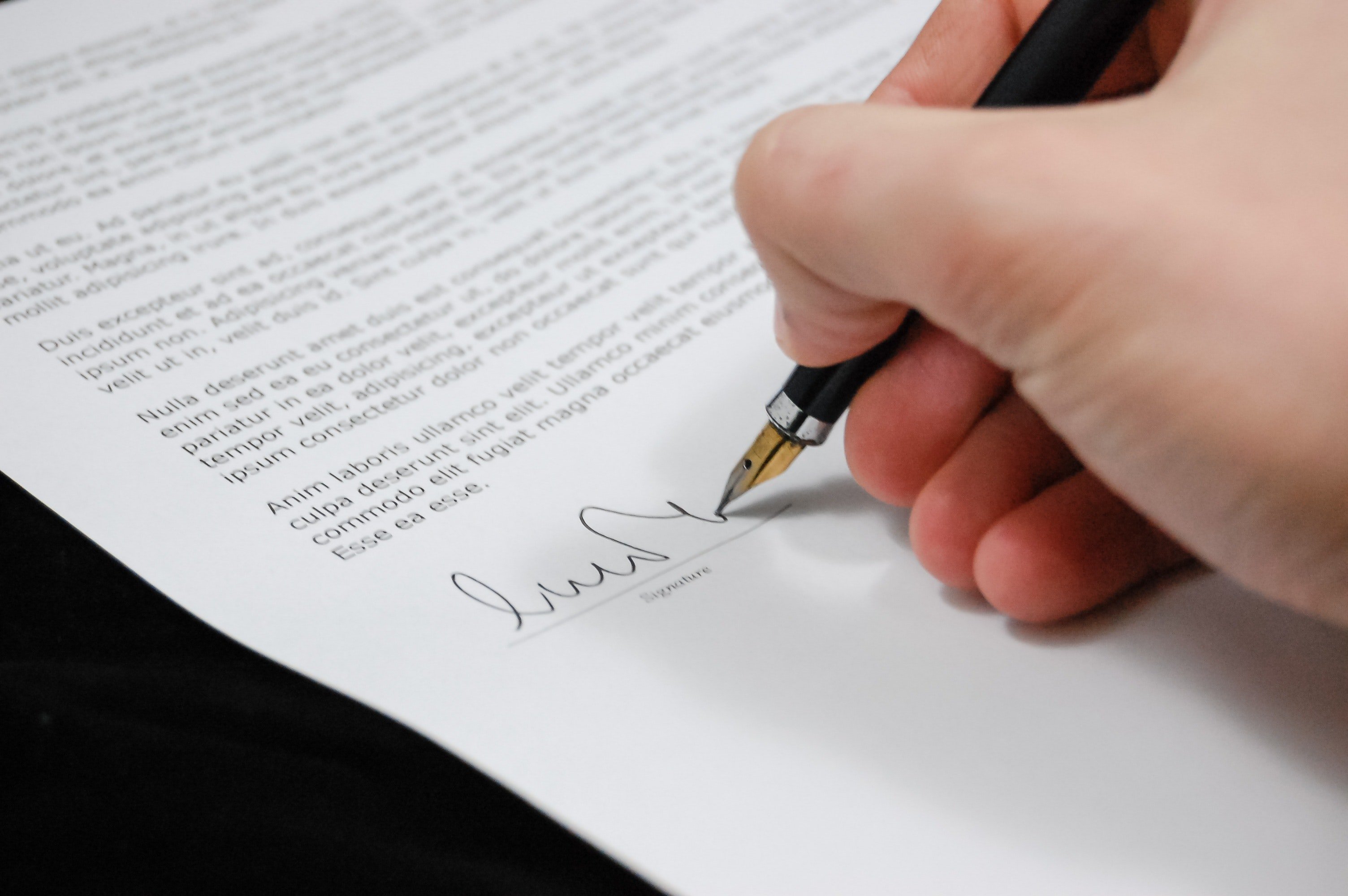 Una persona firma al pie de un documento. | Foto: Pexels
