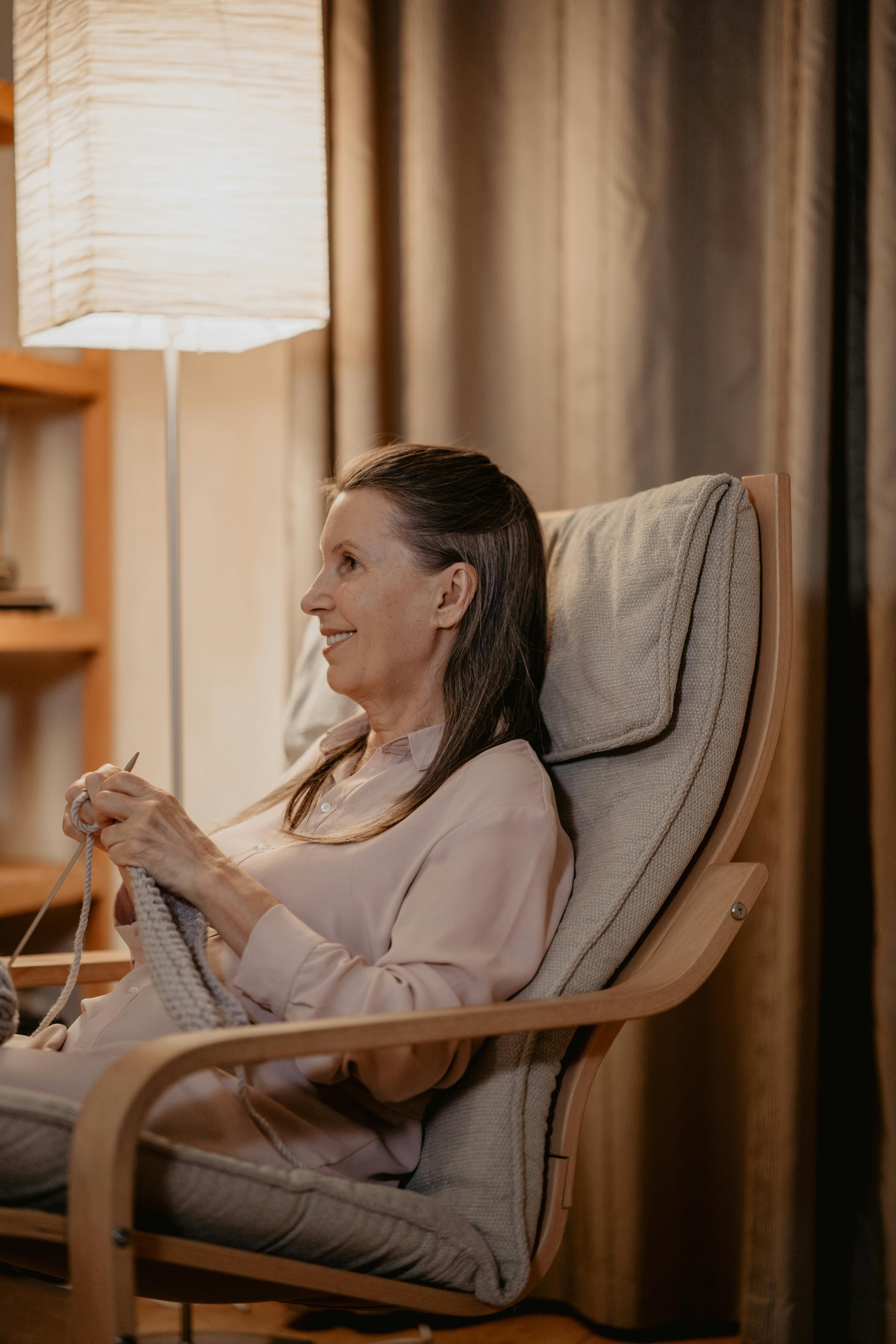 Elderly woman seated on a chair knitting | Source: Pexels