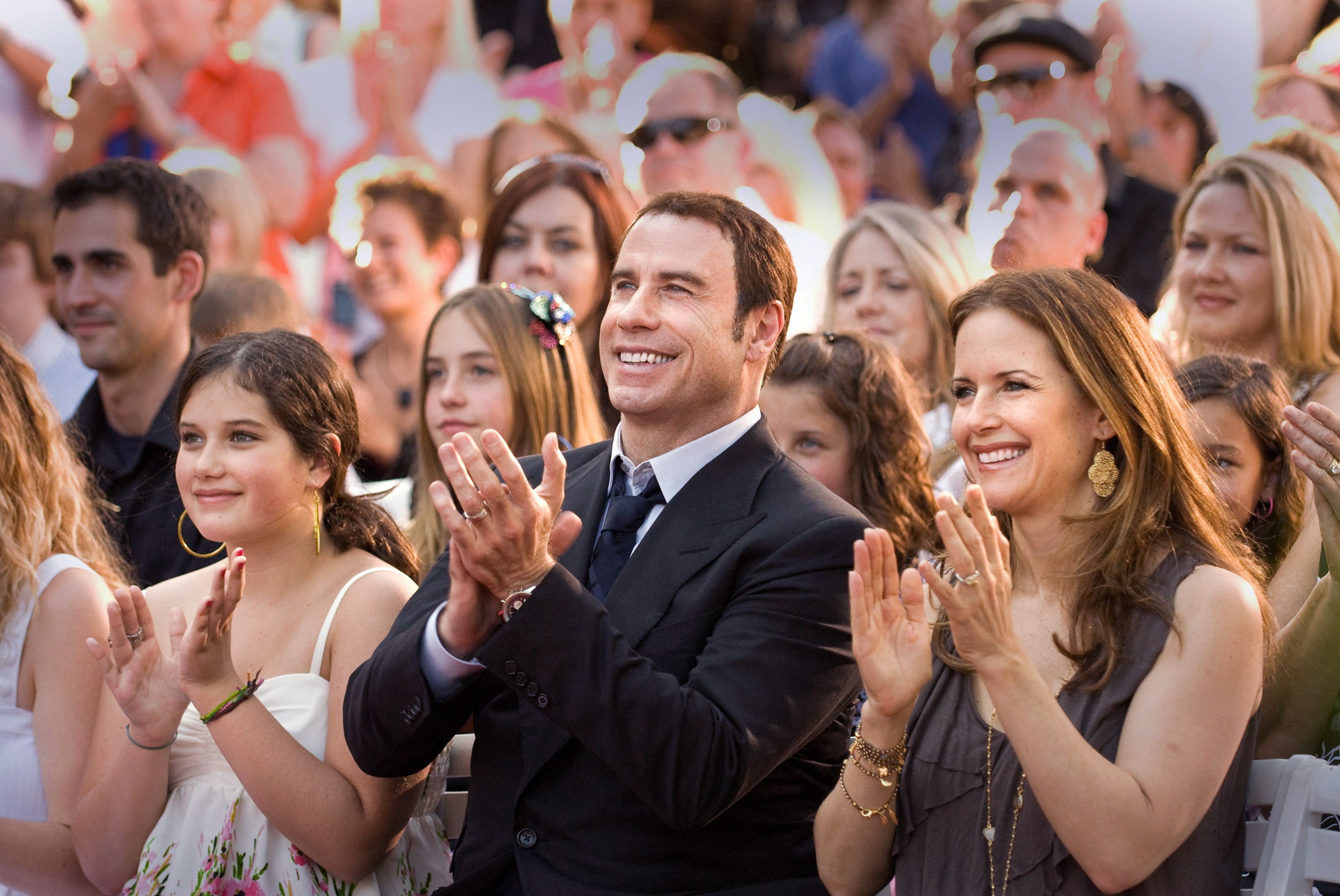 John Travolta (C), daughter Ella Bleu (L) and wife Kelly Preston applaud speakers at the opening of a Scientology Mission on May 29, 2011 in Ocala, Florida. | Source: Getty Images