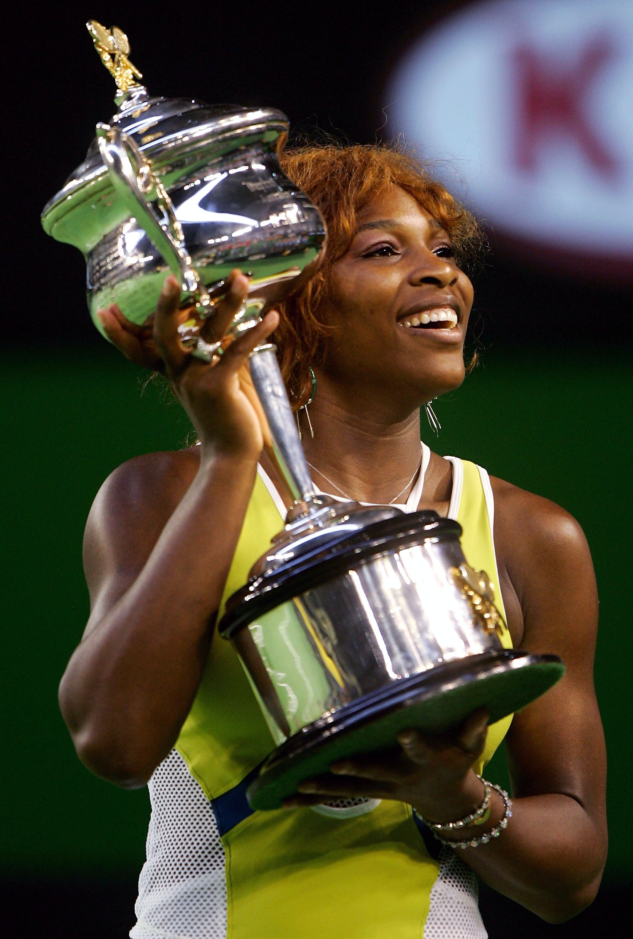 Wearing a bright orange and white tennis dress, Serena Williams celebrated her Australian Open victory in January 2005 in Melbourne. She waved to fans while holding the trophy, beaming with pride after the hard-fought match.