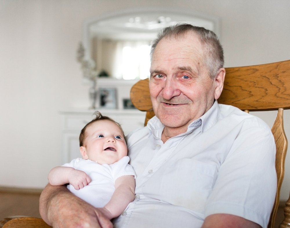 Portrait of a great grandfather holding a newborn baby girl. | Photo: Shutterstock