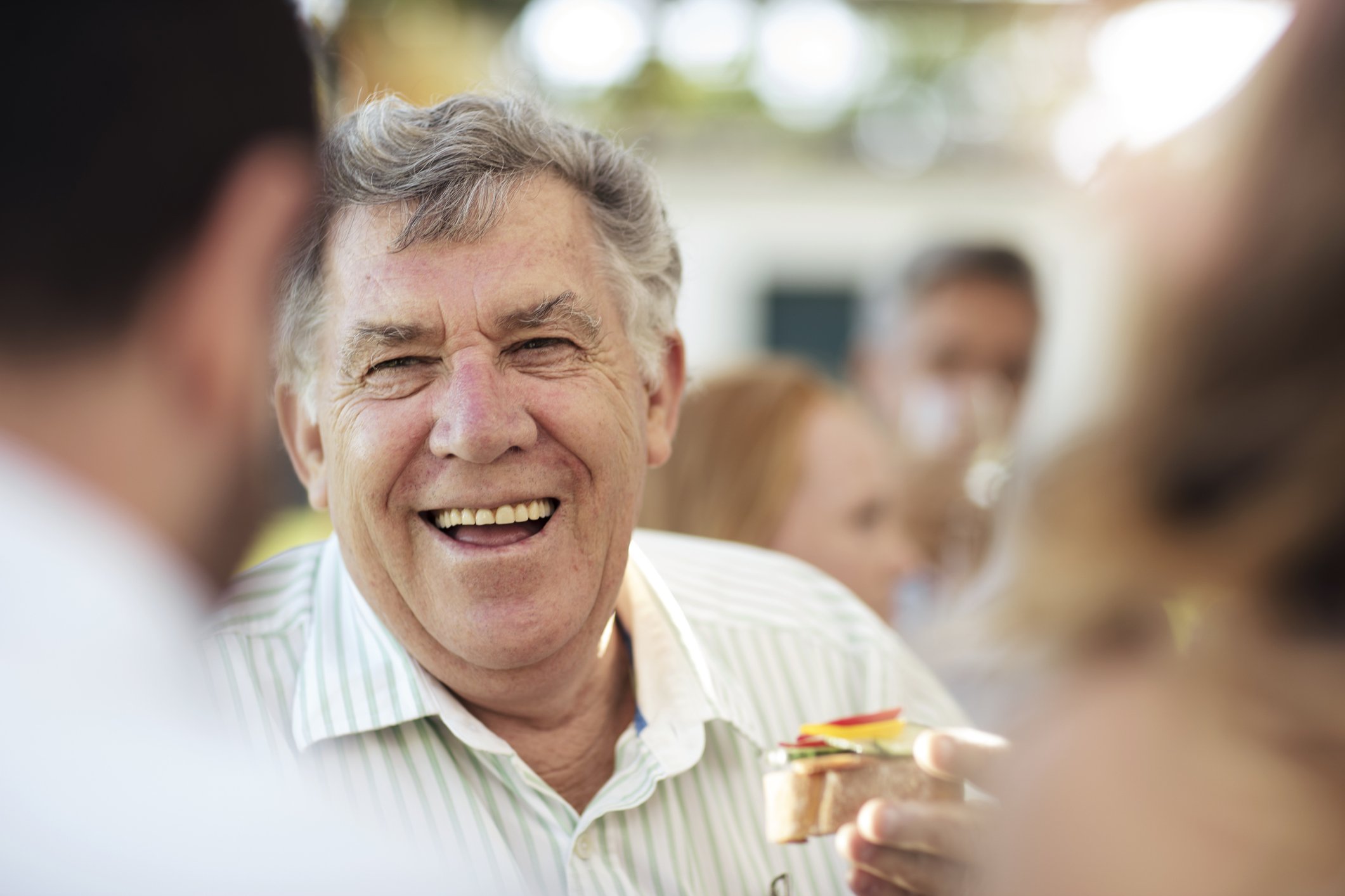 Glücklicher älterer Mann, der auf einer Gartenparty sozialisiert | Quelle: Getty Images