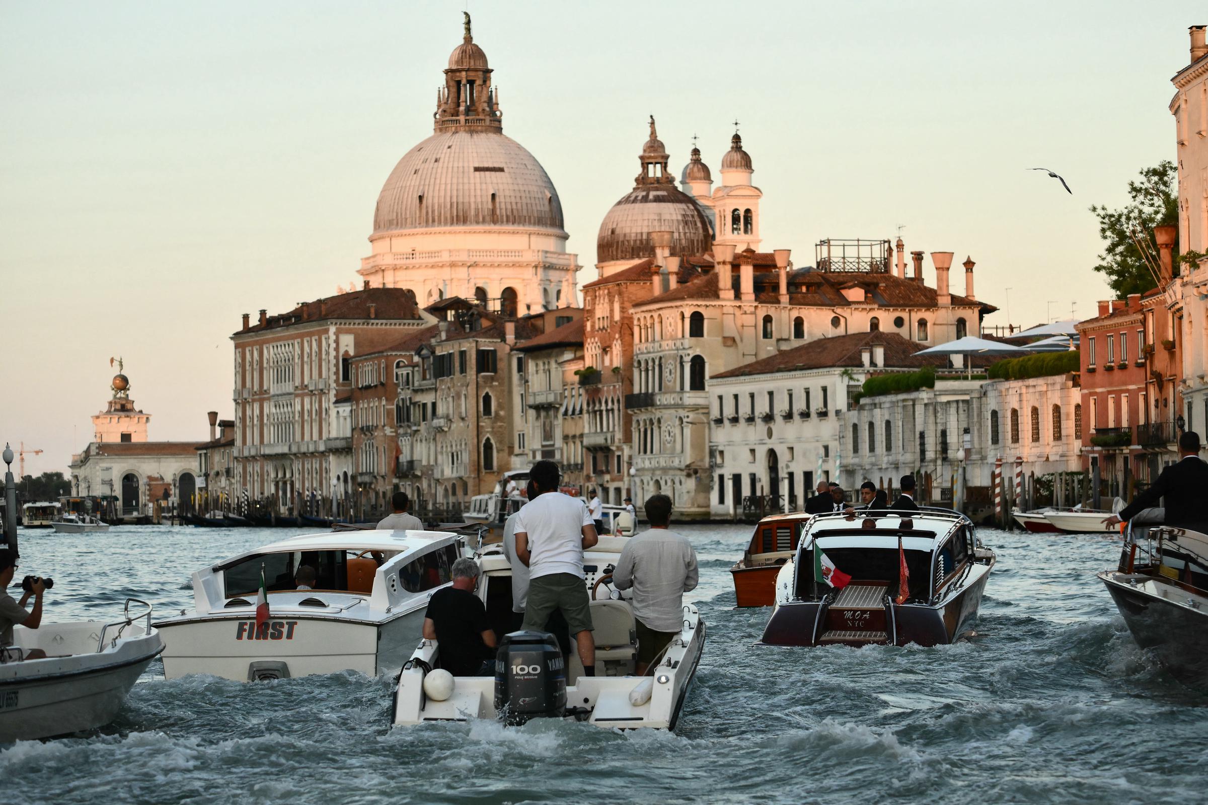 Motorboats weave along the canal as the golden light illuminates Venice’s grand domes and historic facades, capturing the lively scene trailing Jeff Bezos and Lauren Sánchez’s water taxi.