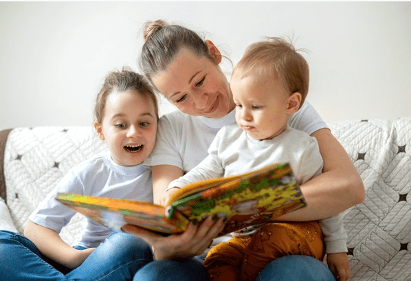 Madre leyéndole un libro a dos niños. │ Foto: Freepik