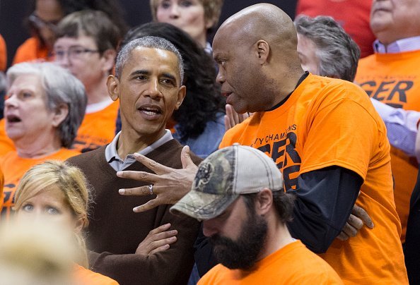 Barack Obama (L) sits beside his brother-in-law Craig Robinson while attending the Green Bay versus Princeton women's college basketball game in the first round of the NCAA tournament, March 21, 2015, in College Park, Maryland. | Source: Getty Images.