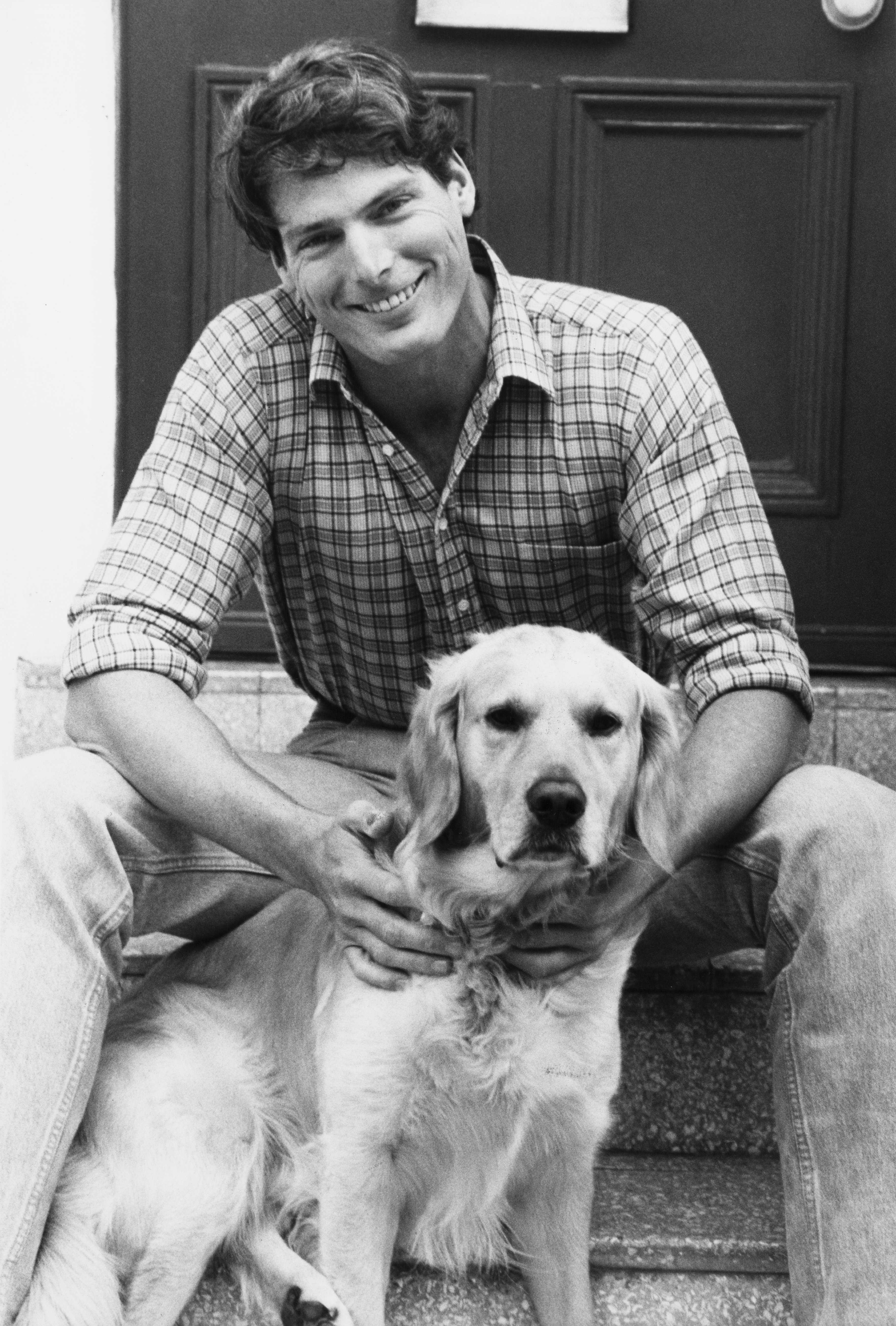Christopher Reeve posing while seated on a staircase with his dog. / Source: Getty Images