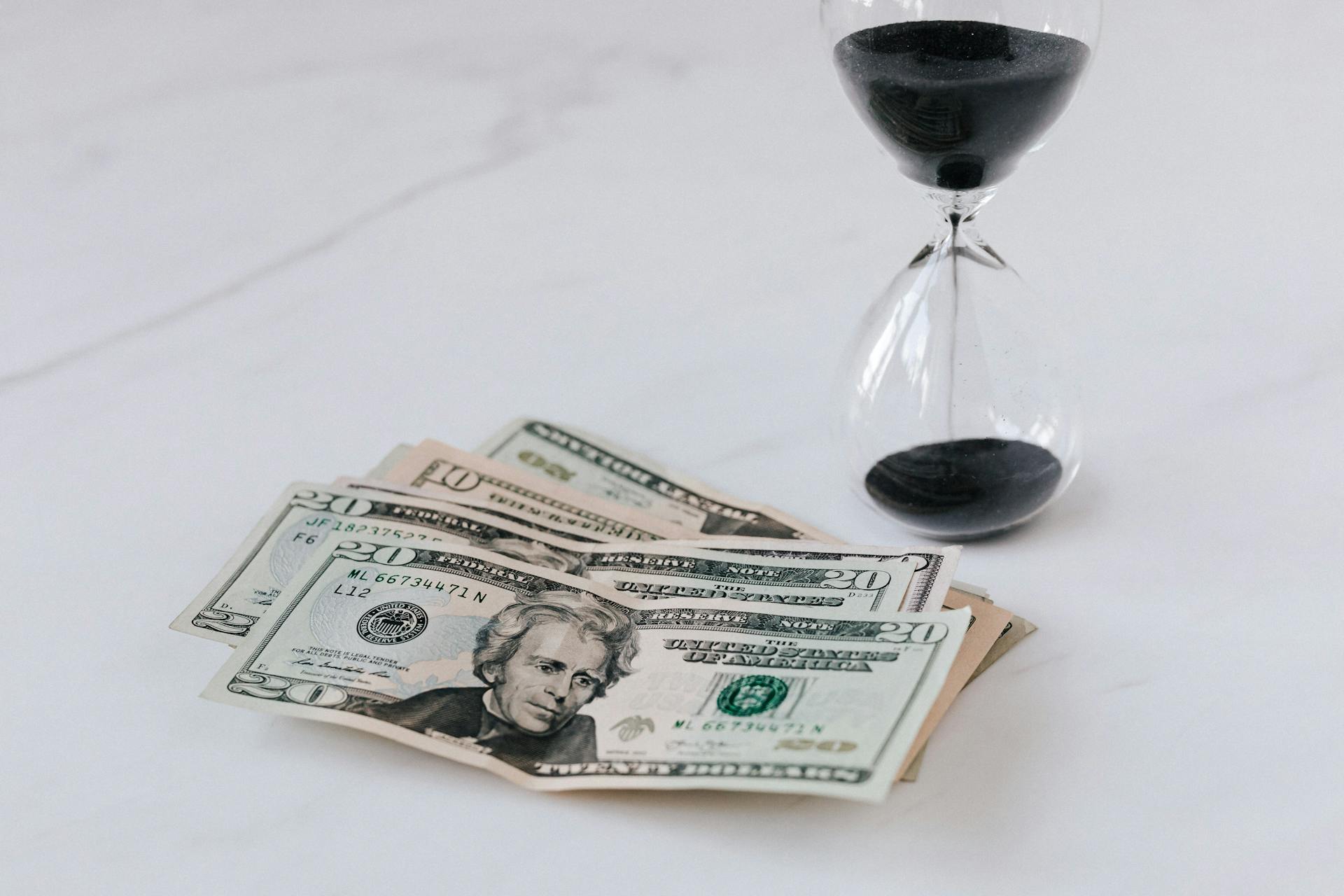 An hourglass lying near a heap of banknotes | Source: Pexels