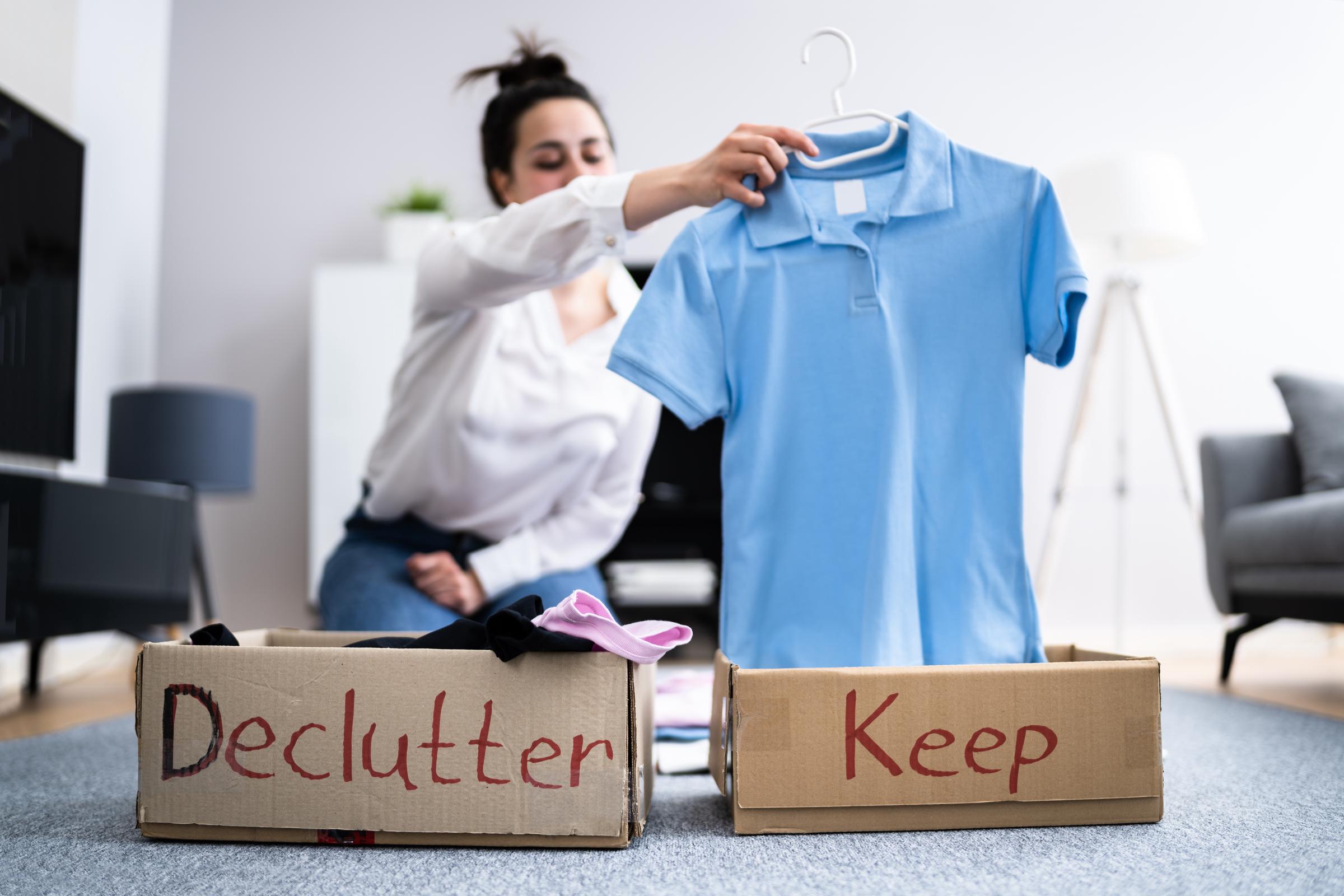 A woman sorting clothes with two boxes, one for decluttering, one for keeping | Source: Shutterstock