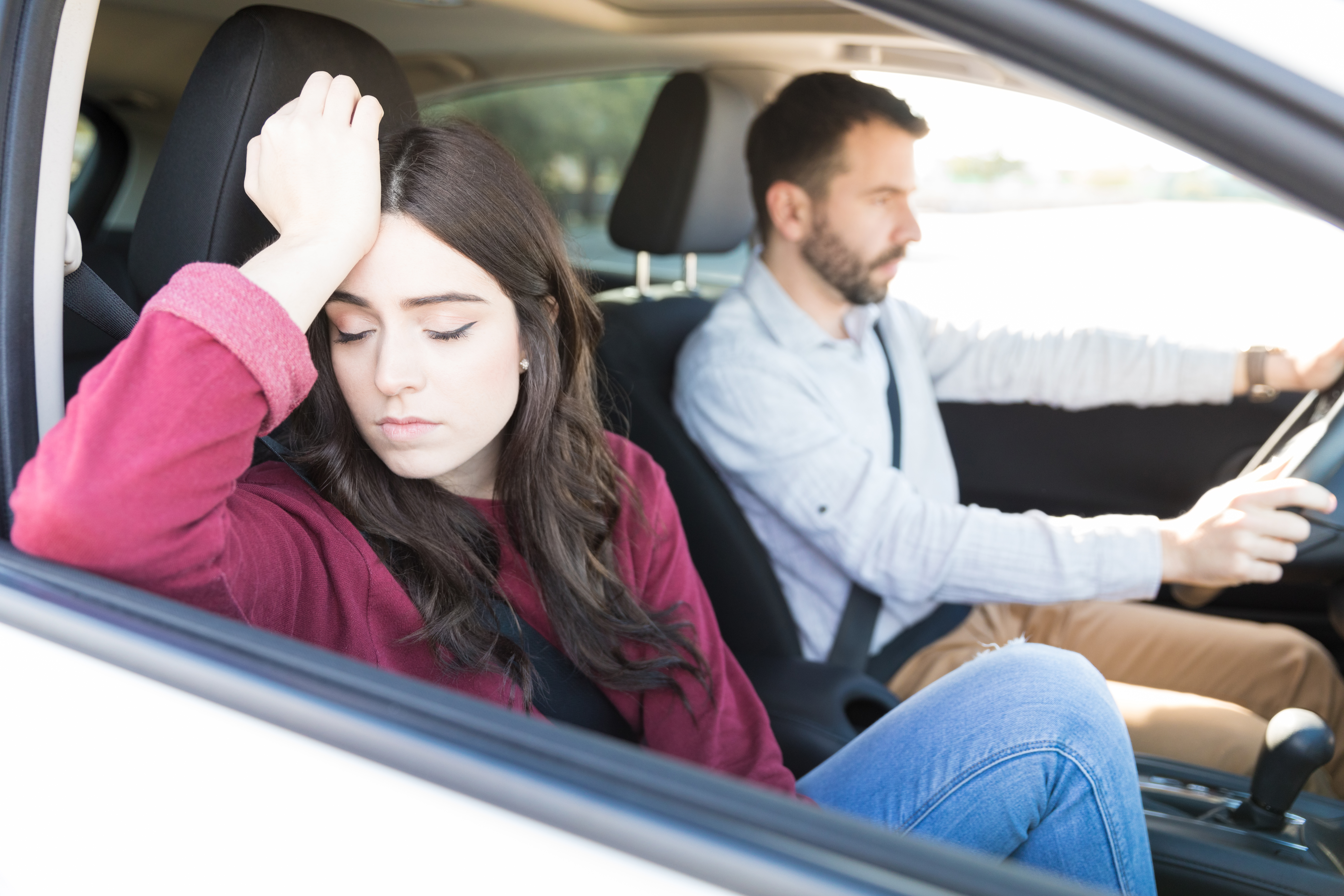 Sad attractive young woman sitting in car with boyfriend during drive | Source: Shutterstock.com