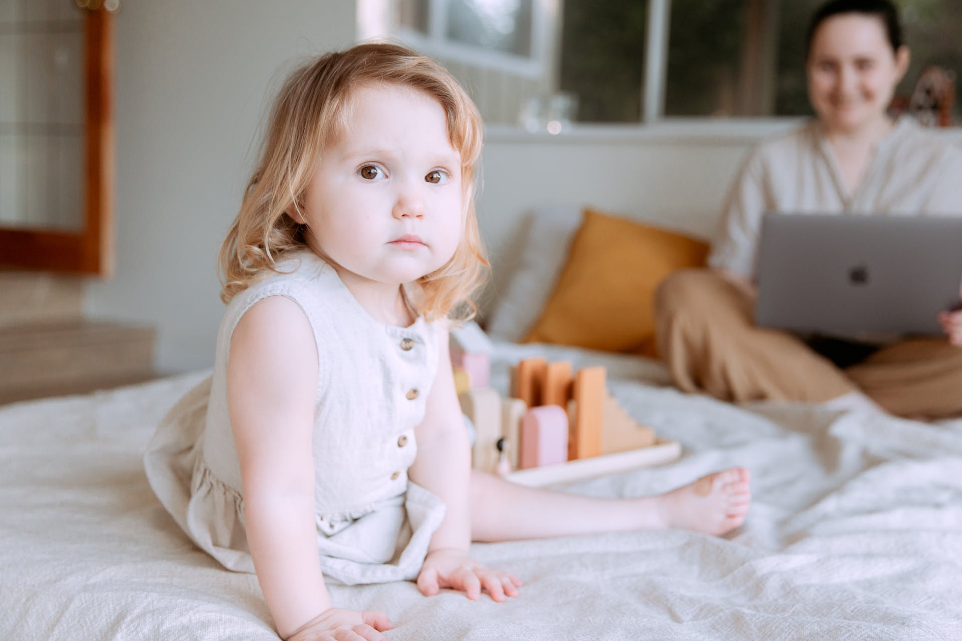 A little girl sitting on a bed with a woman | Source: Pexels