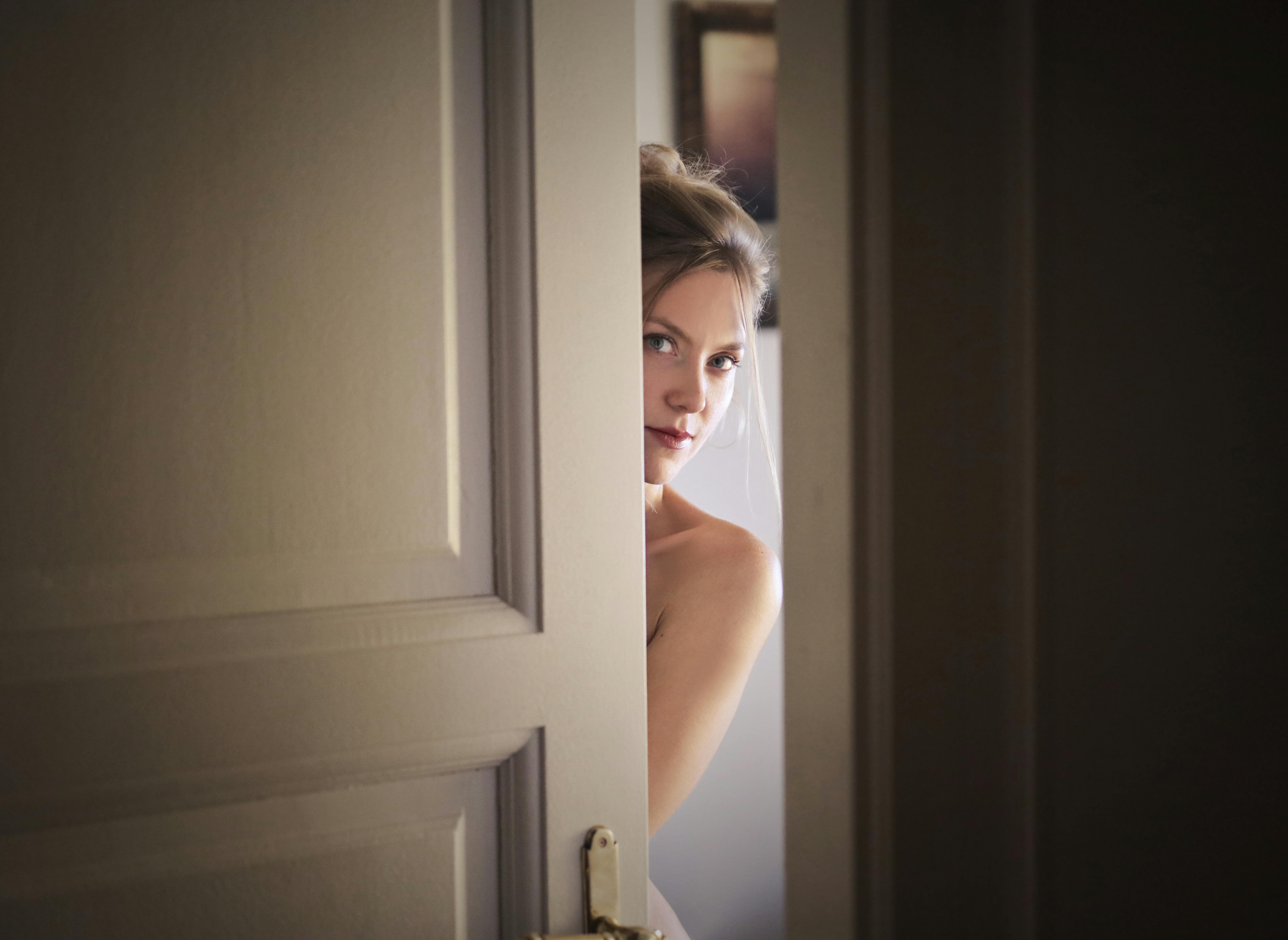 A woman peeking through an open door | Source: Pexels