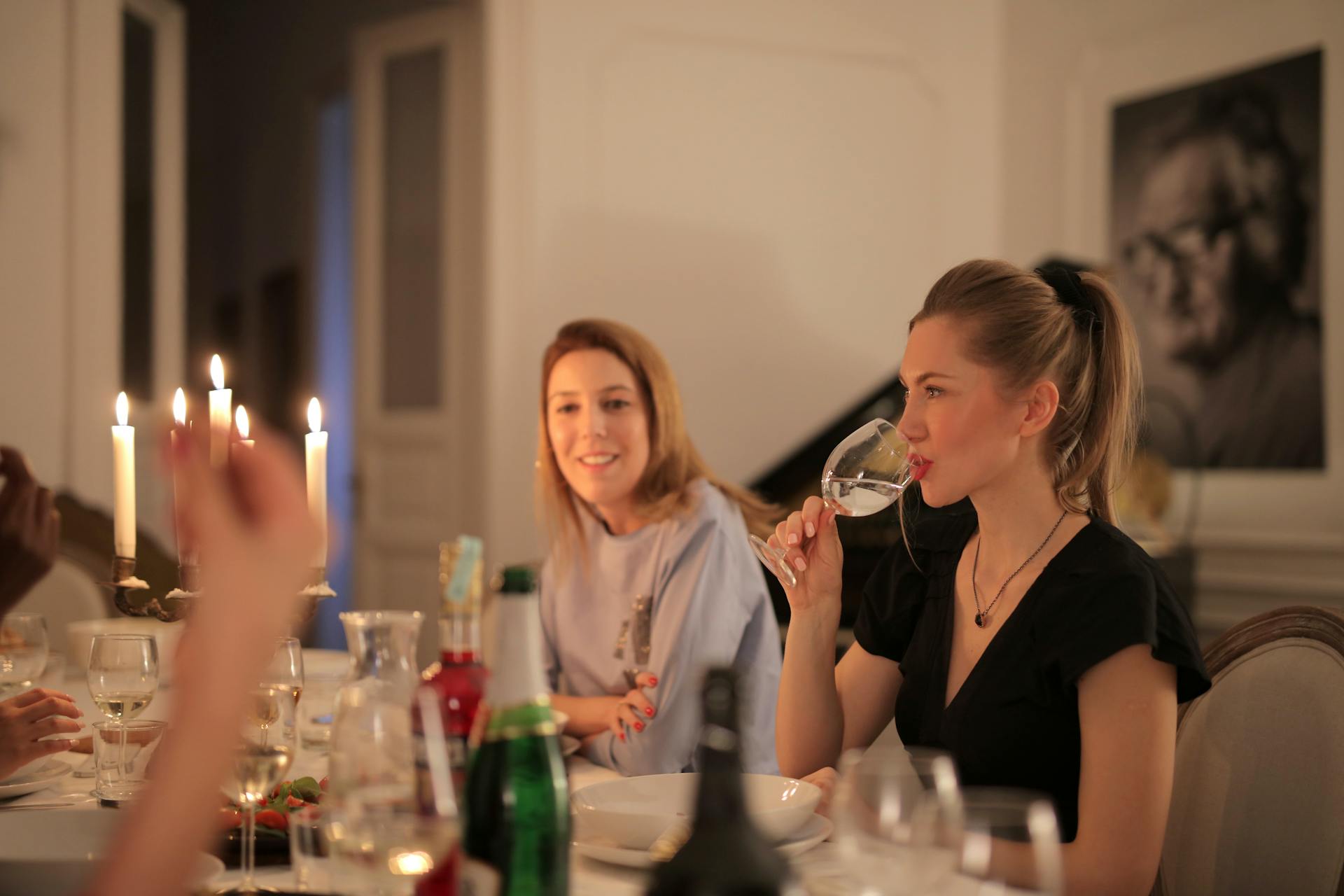 A woman drinking wine while having dinner with her friends | Source: Pexels