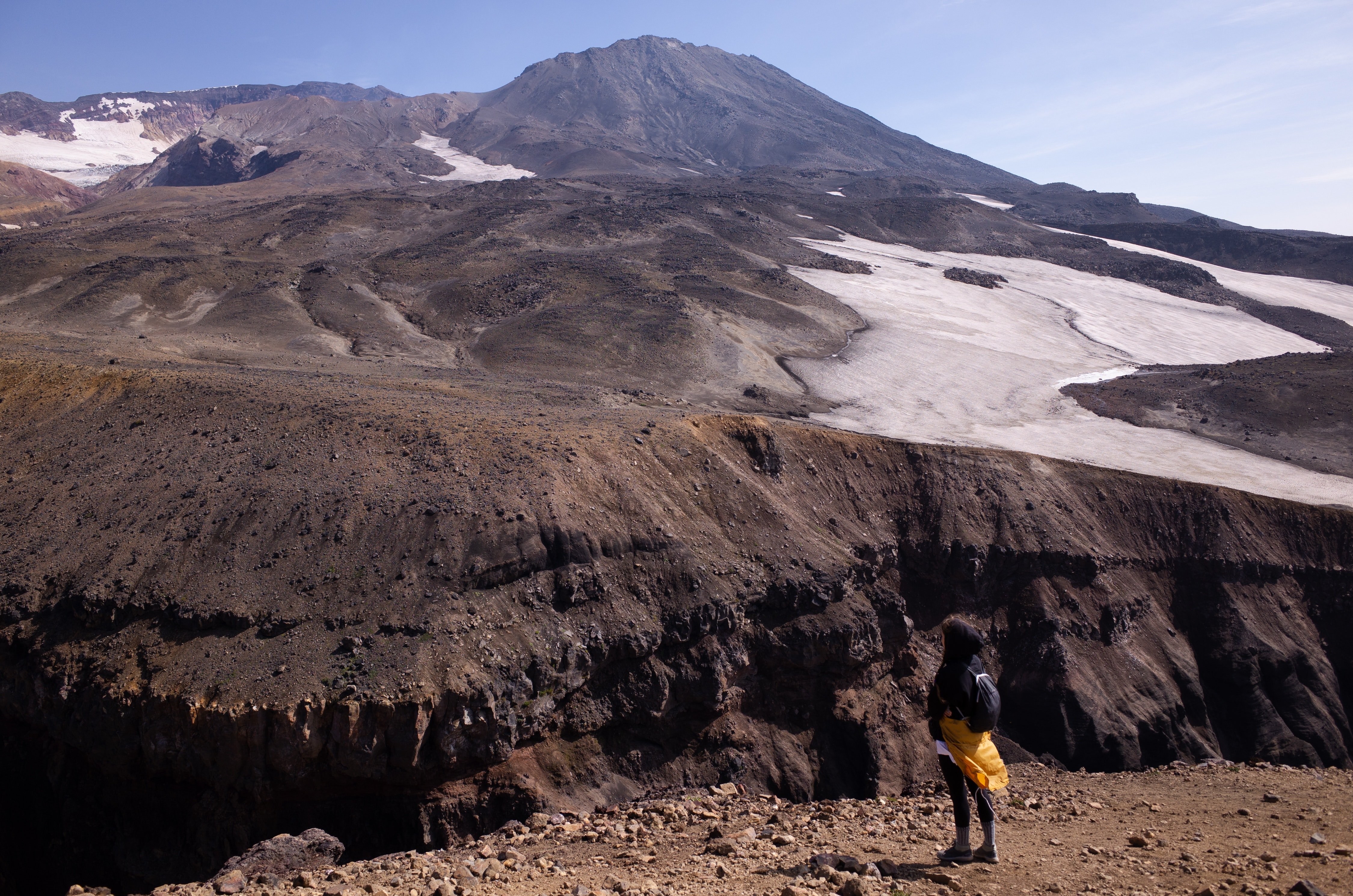 Persona parada frente a un acantilado en una montaña. | Foto: Pexels
