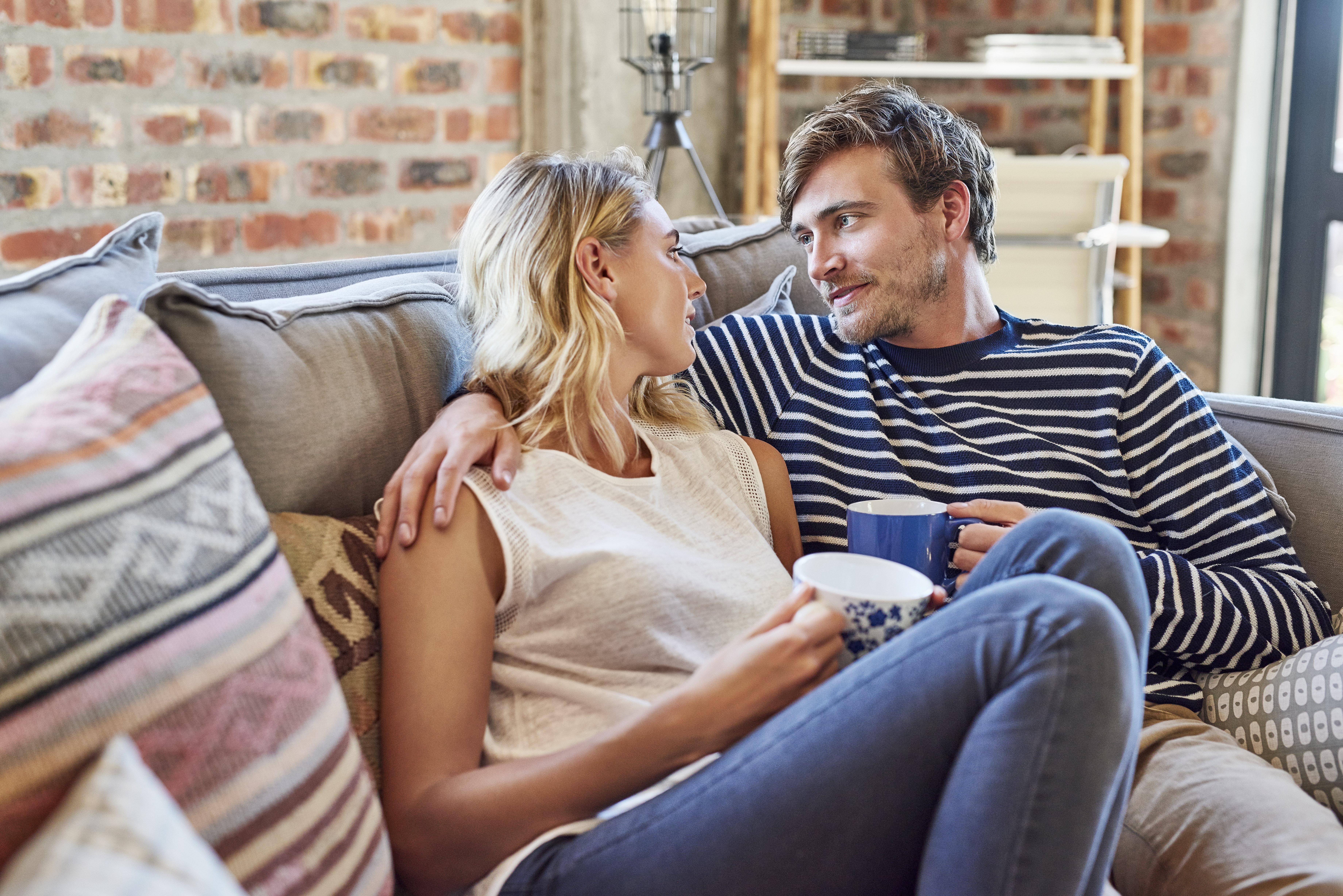 Romantic couple looking at each other on sofa | Source: Getty Images