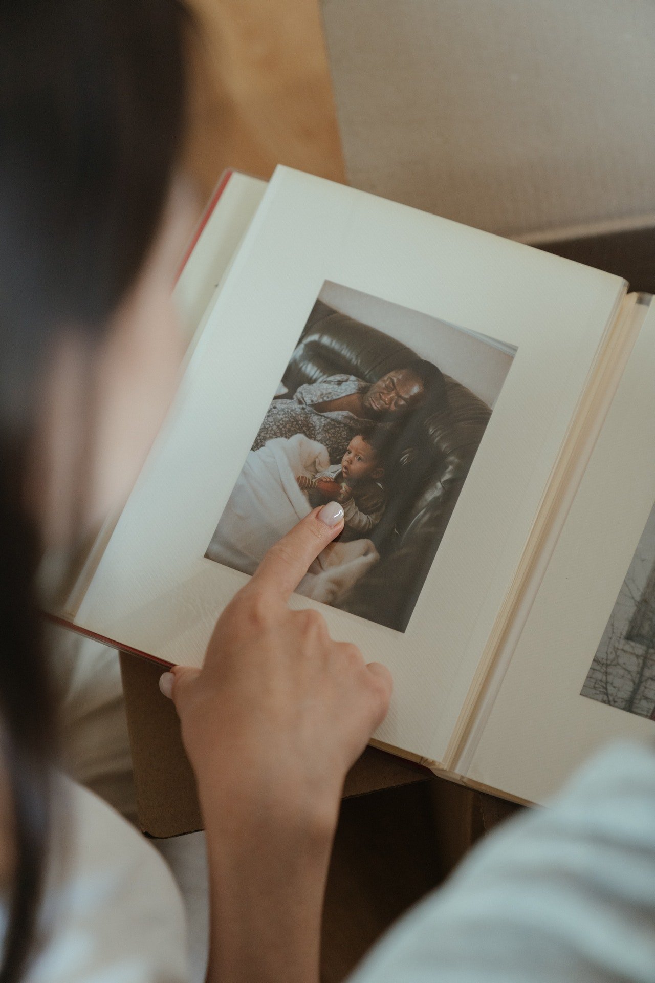 Una mujer señala una fotografía de un álbum. | Foto: Pexels
