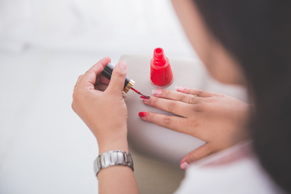 Mujer aplicándose esmalte de uñas rojo. | Foto: Shutterstock