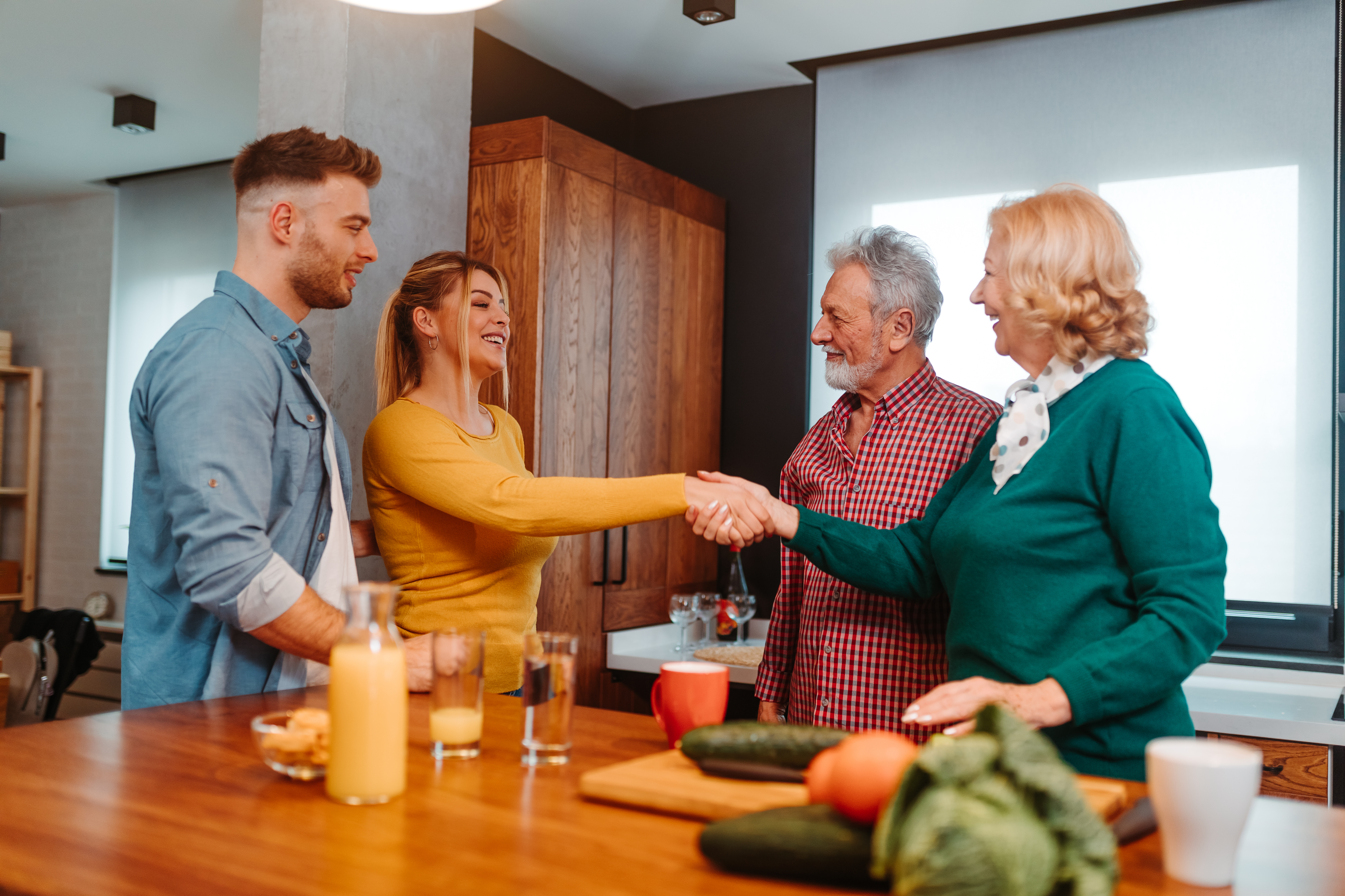 A young woman exchanges a handshake with her partner's mom as he and his dad look on | Source: Shutterstock