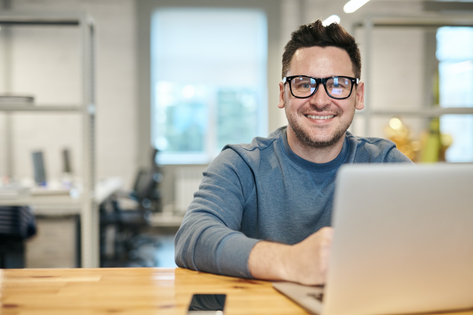A man smiling while working on his laptop | Source: Pexels