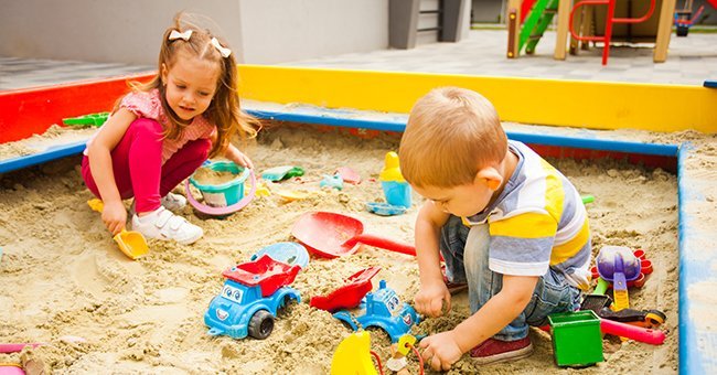Deux jeunes enfants jouant dans un bac à sable. | Photo : Shutterstock