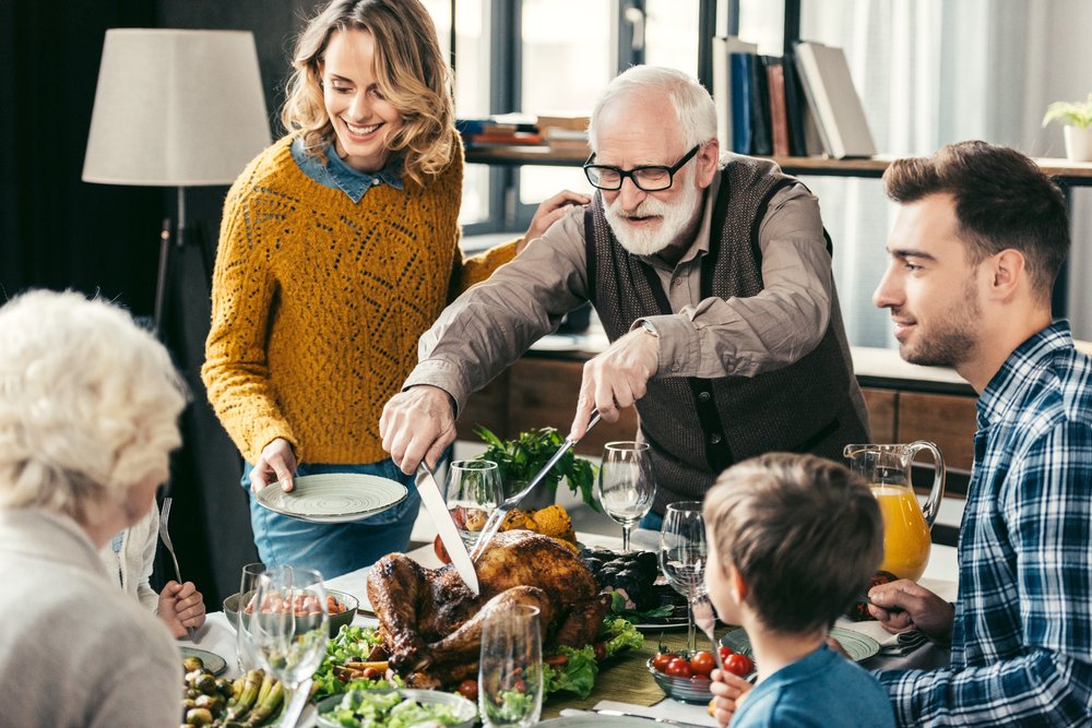 Grandfather cutting turkey for family’s dinner | Photo: Shutterstock/LightField Studios