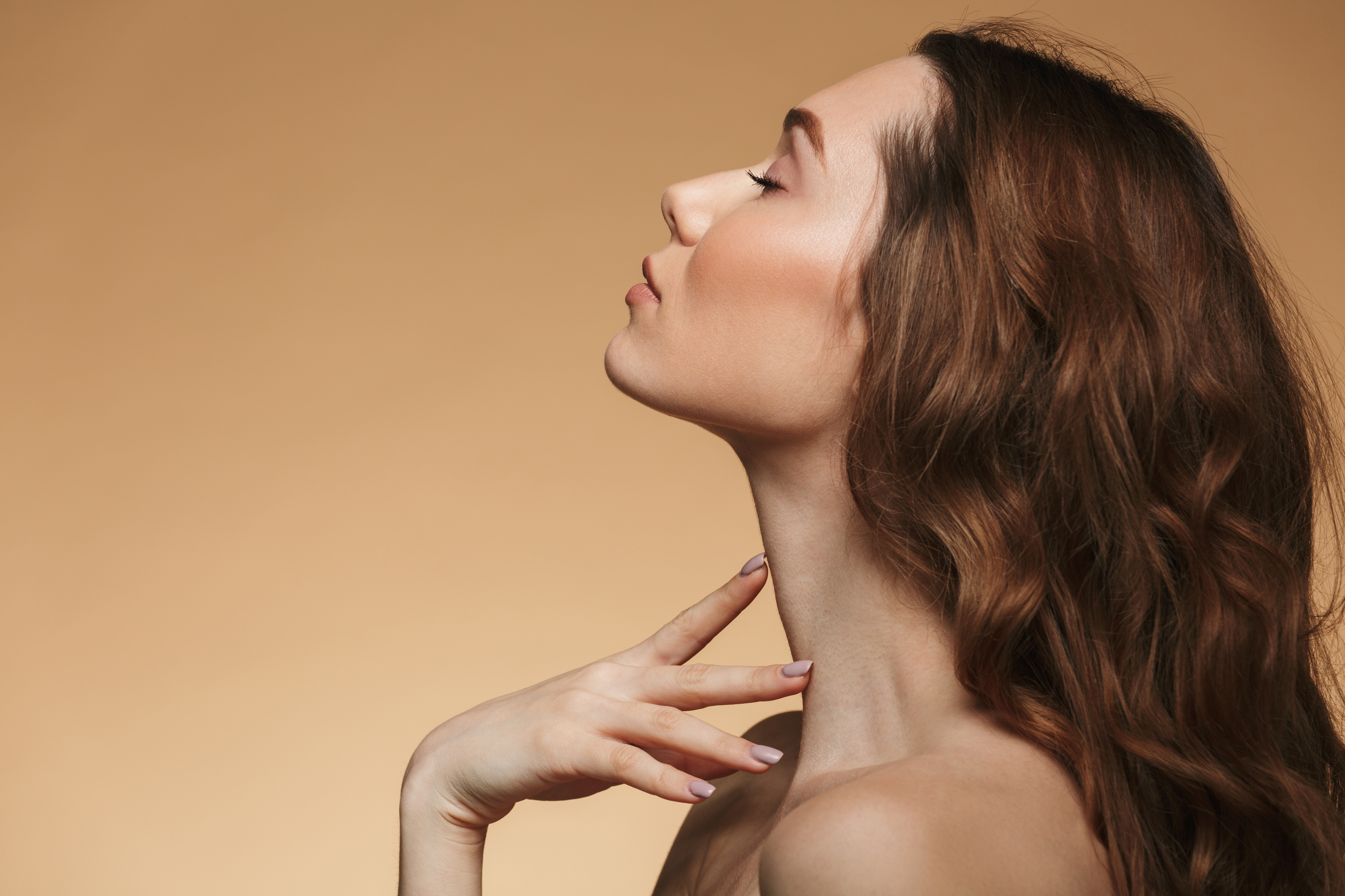 Woman with deep brown hair closing her eyes as she tilts her head back | Source: Shutterstock