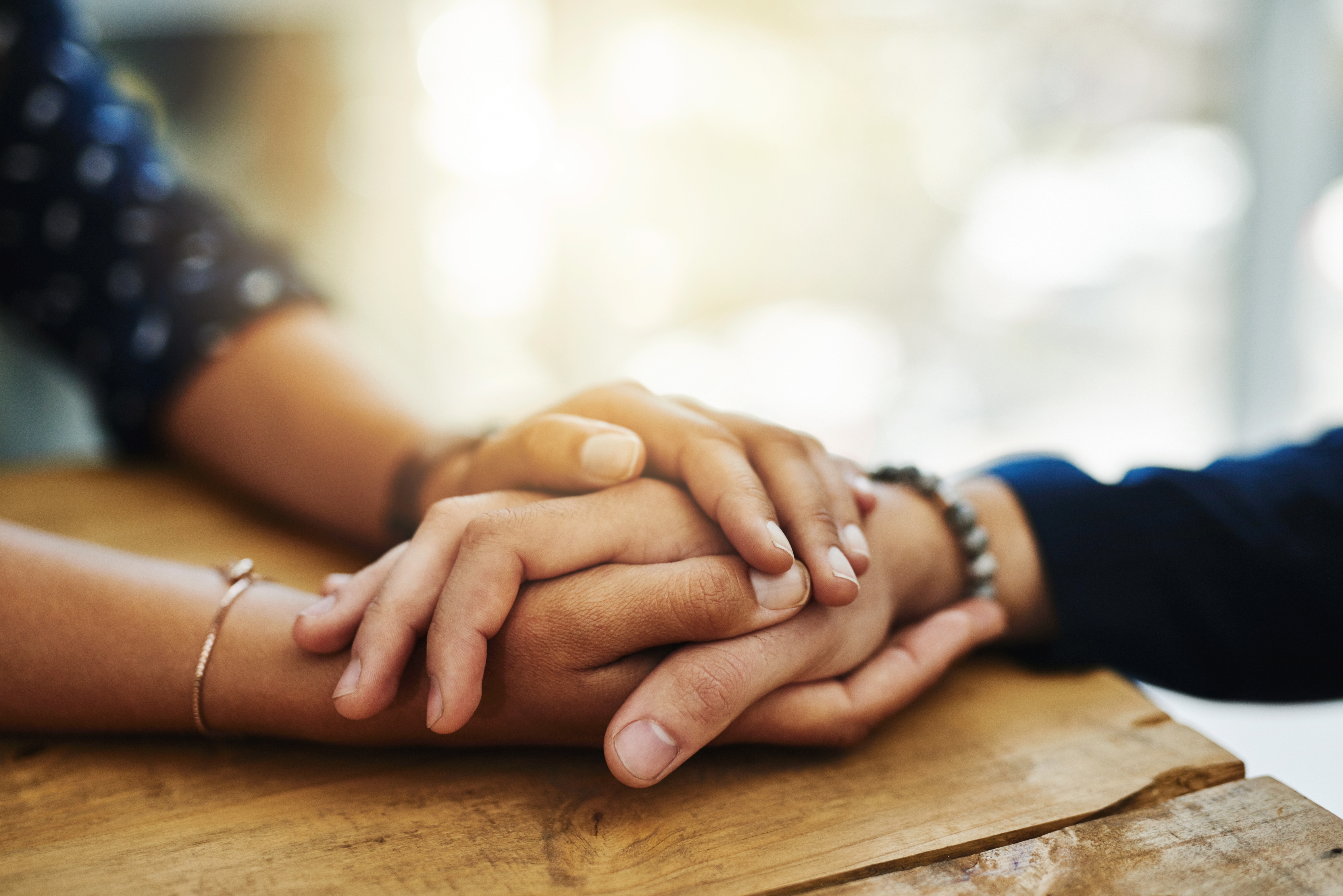 A close-up of two friends holding hands in a show of support | Source: Shutterstock