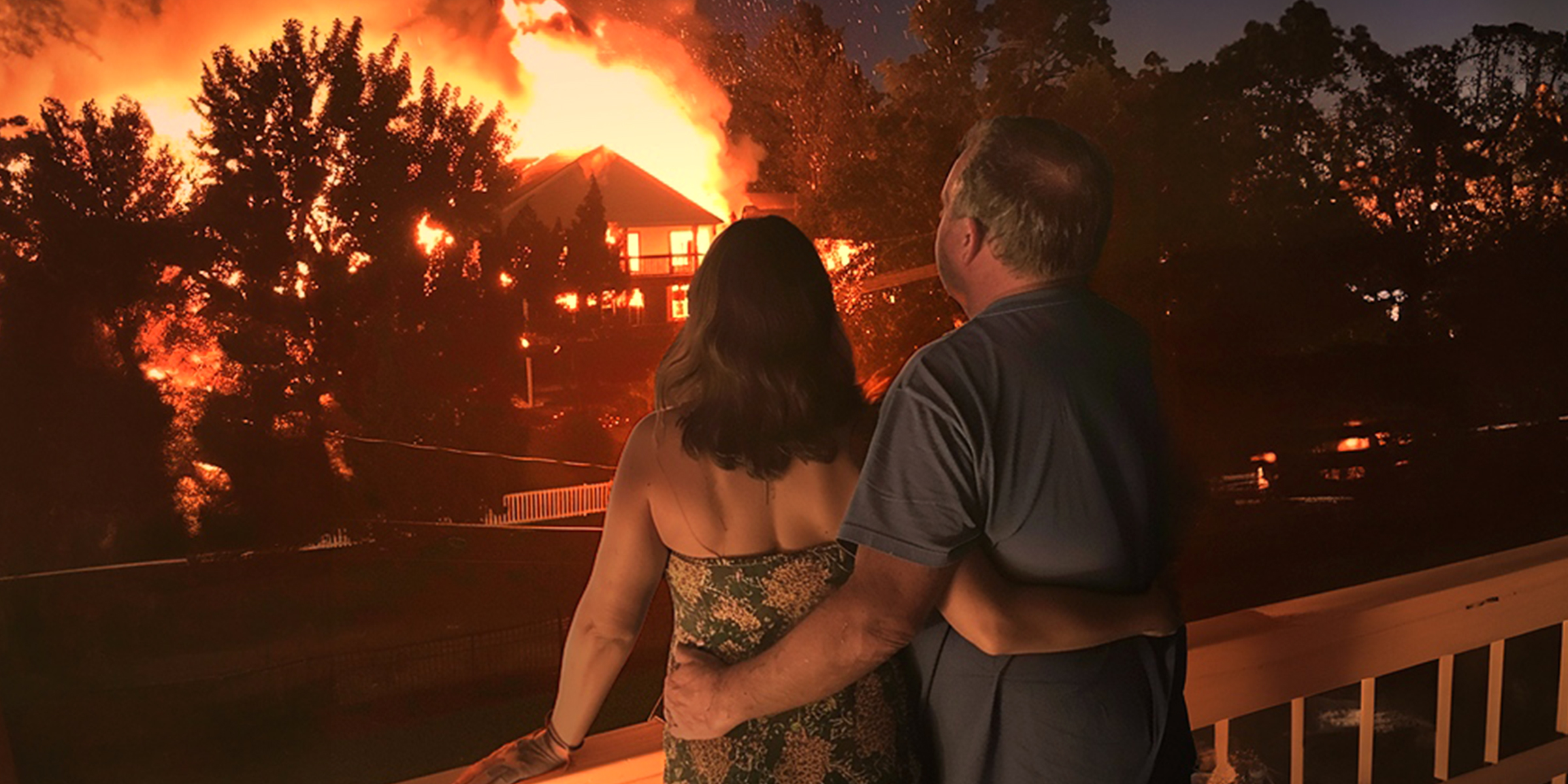 A couple watching a house on fire in their neighborhood | Source: Midjourney