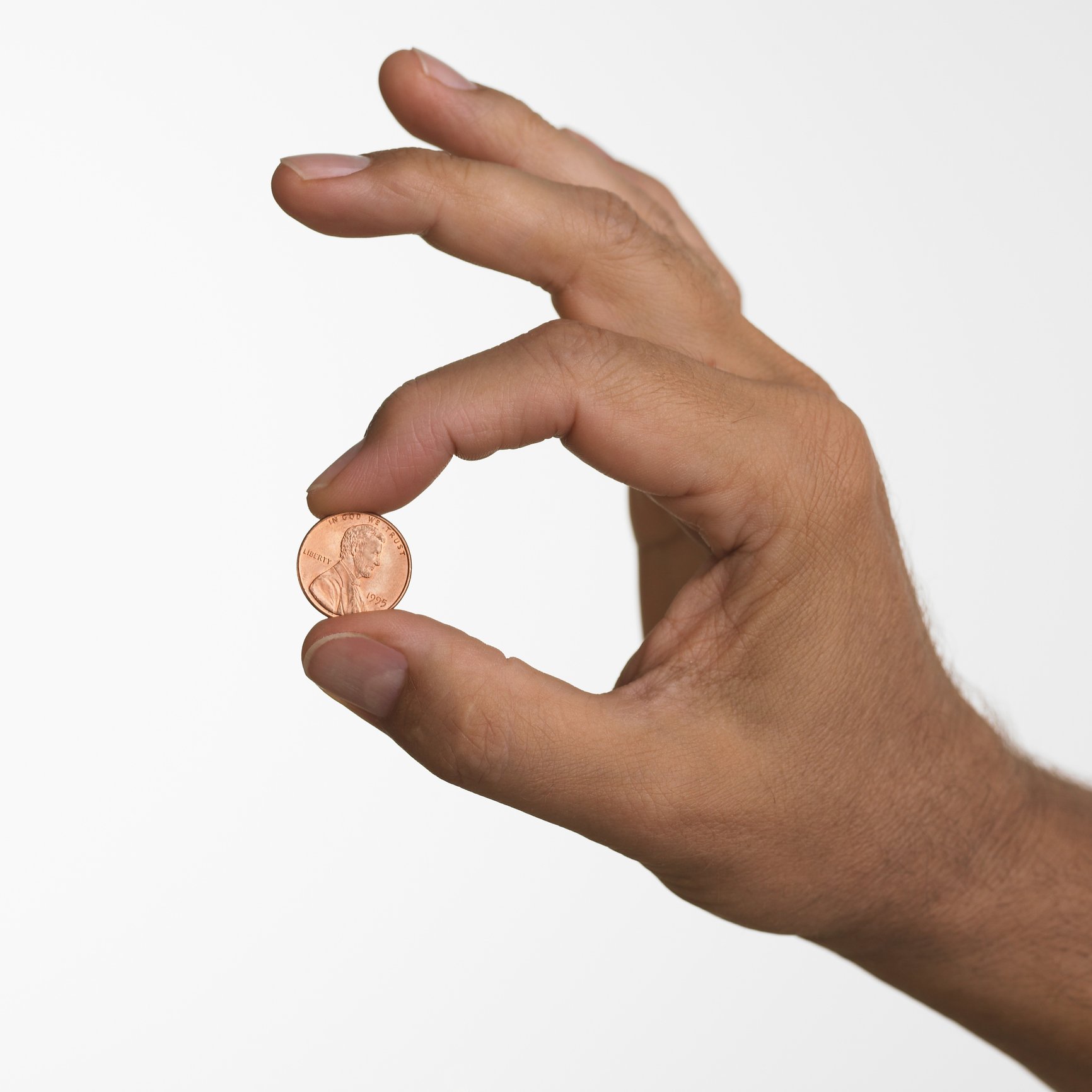 Close up studio shot of man holding penny | Photo: Getty Images