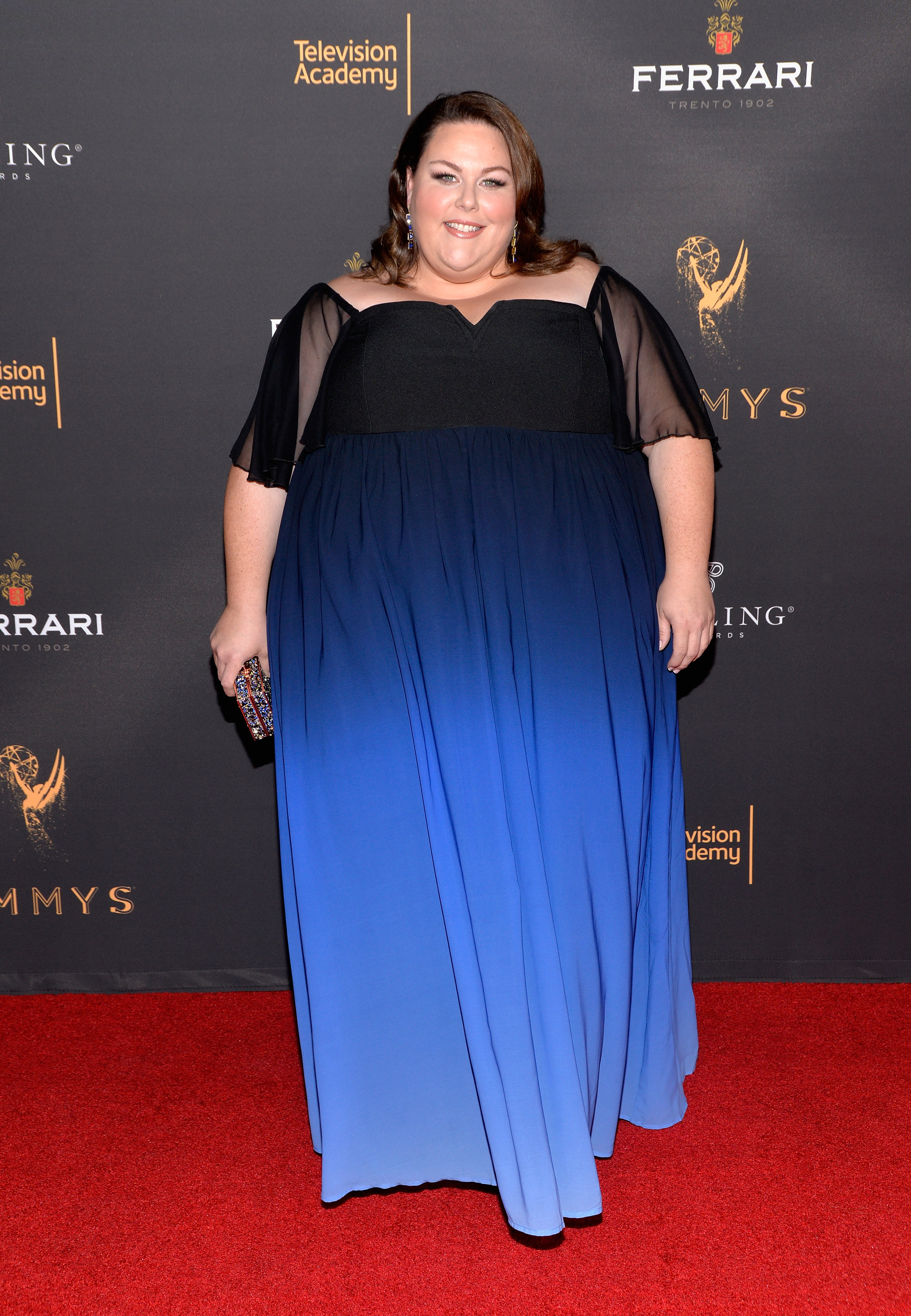 Later that year, Metz wore a black-and-blue floor-length gown with sheer sleeves at a Television Academy event. The formal red carpet image adds another clear comparison point from early in her career.