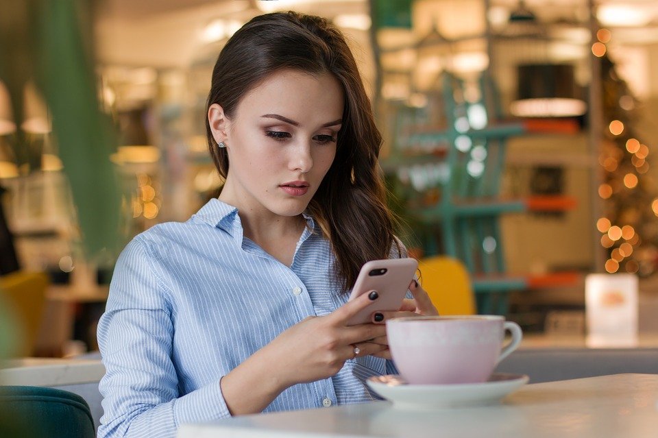 A young woman looking at her cellphone. | Photo: Pixabay