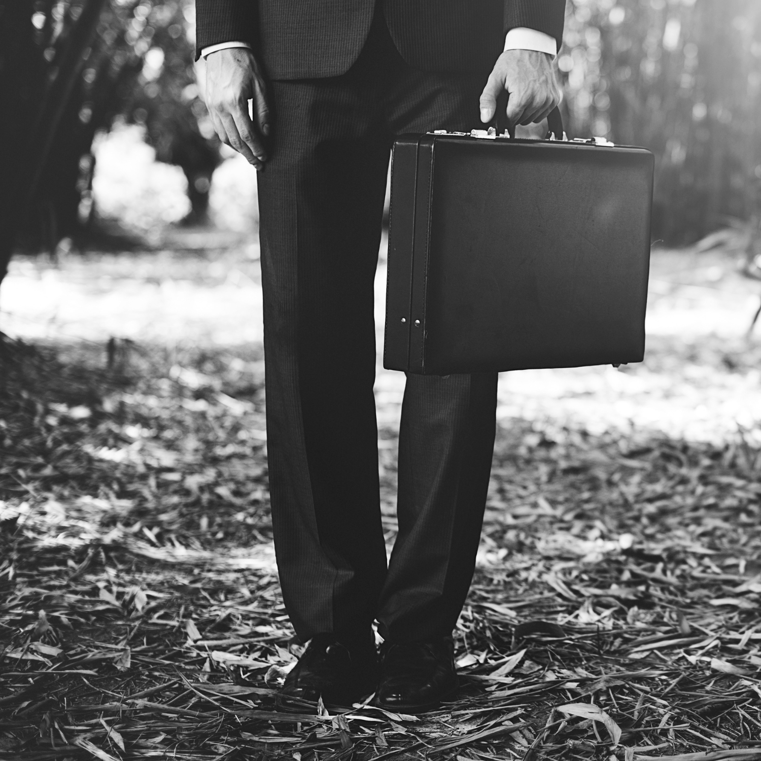 Grayscale shot of a man in a dark suit holding a briefcase | Source: Freepik