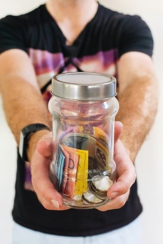 A photo of a man holding a jar and asking for money. | Photo: Unsplash
