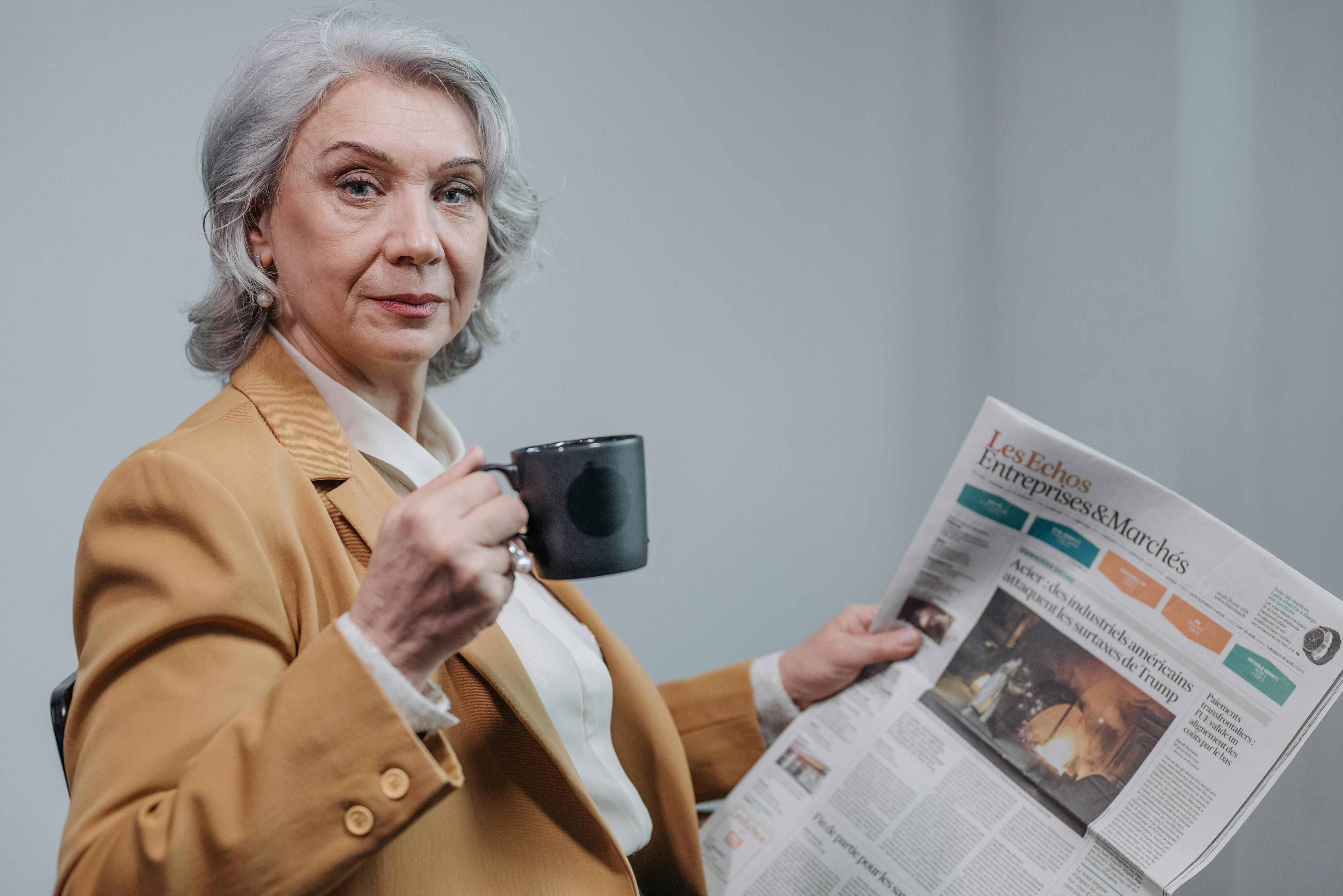 A serious woman having coffee and reading a newspaper | Source: Pexels