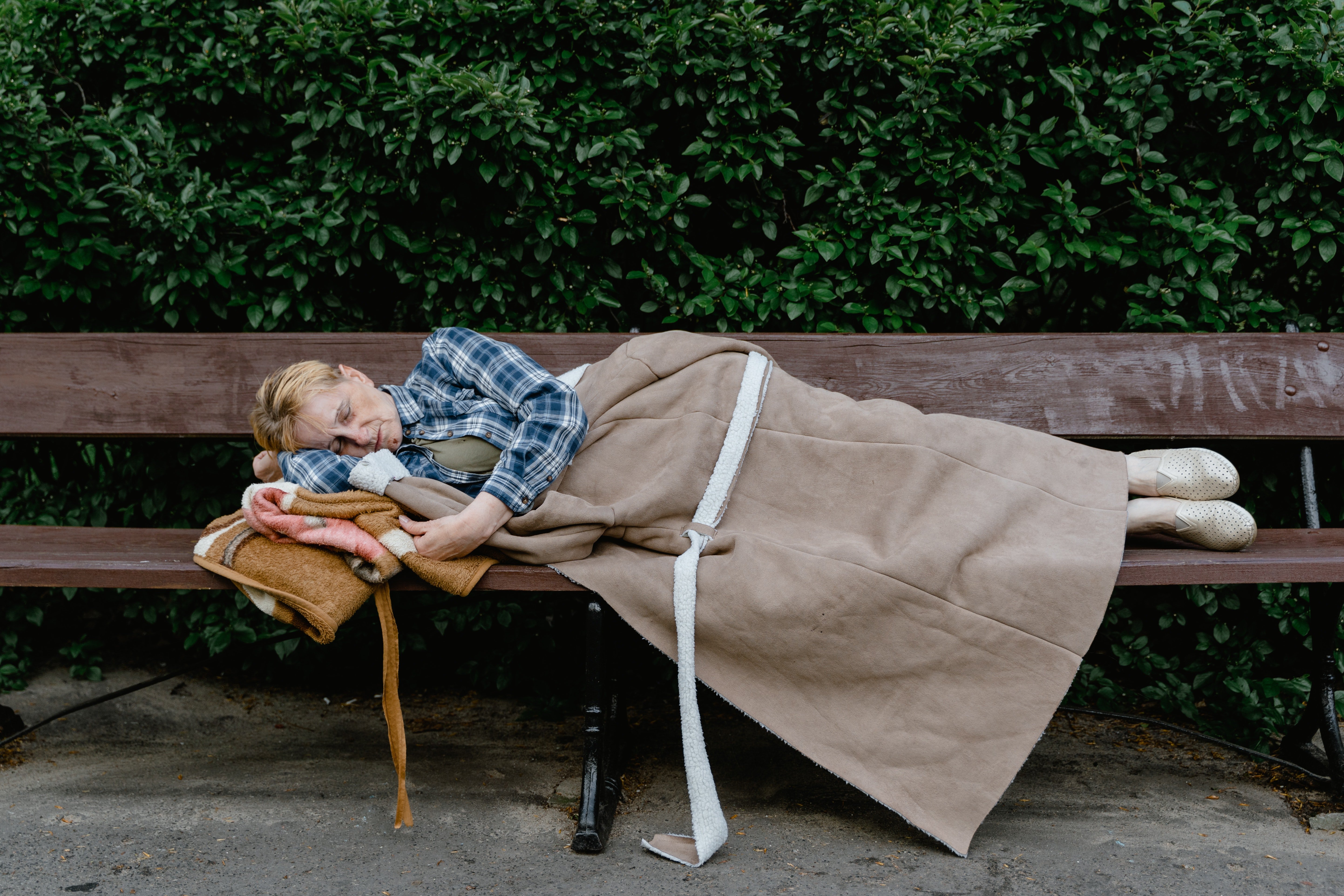 Una mujer mayor sin hogar durmiendo en el banquillo de un parque. | Foto: Pexels