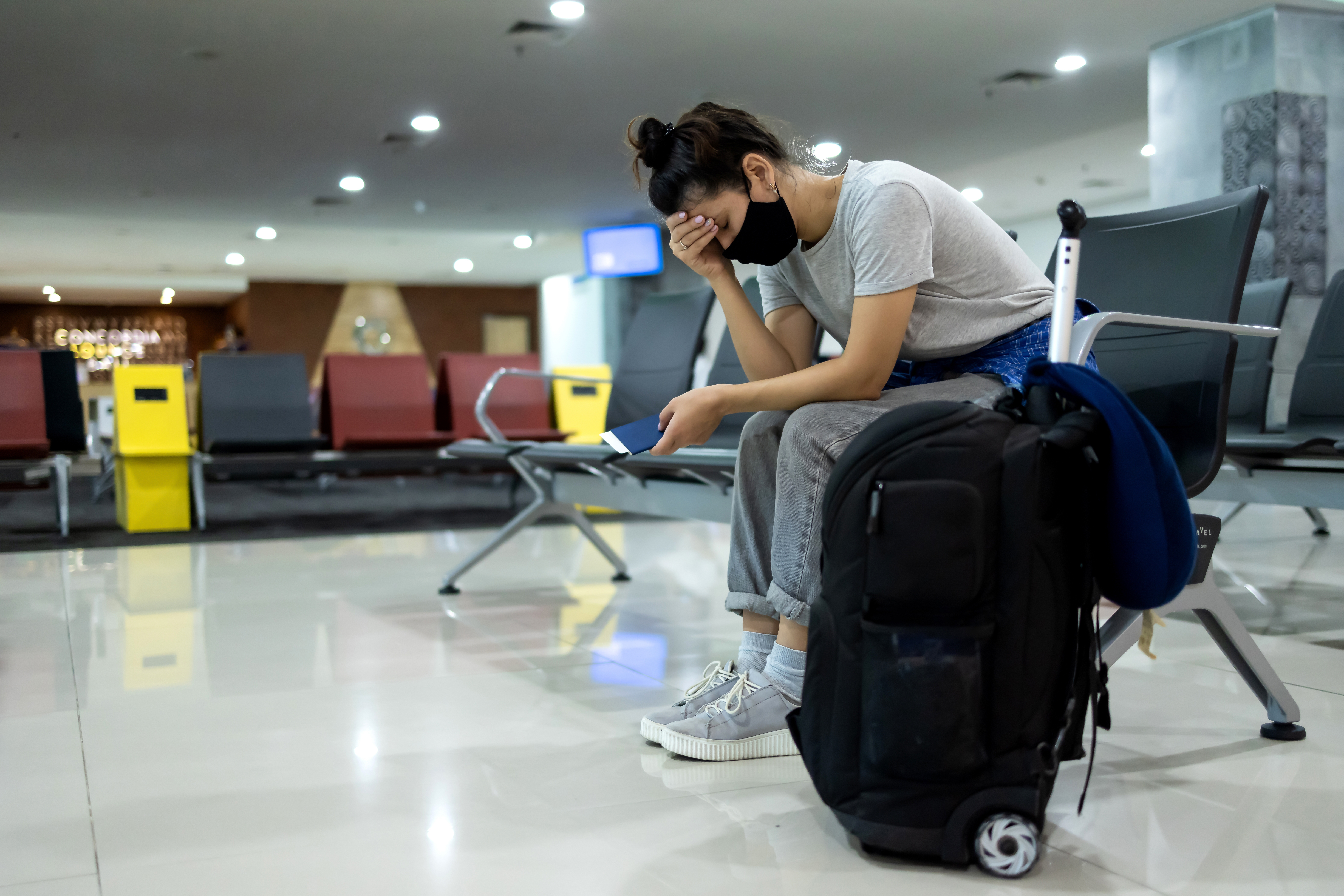 A woman sitting in a waiting lounge with luggage | Source: Shutterstock