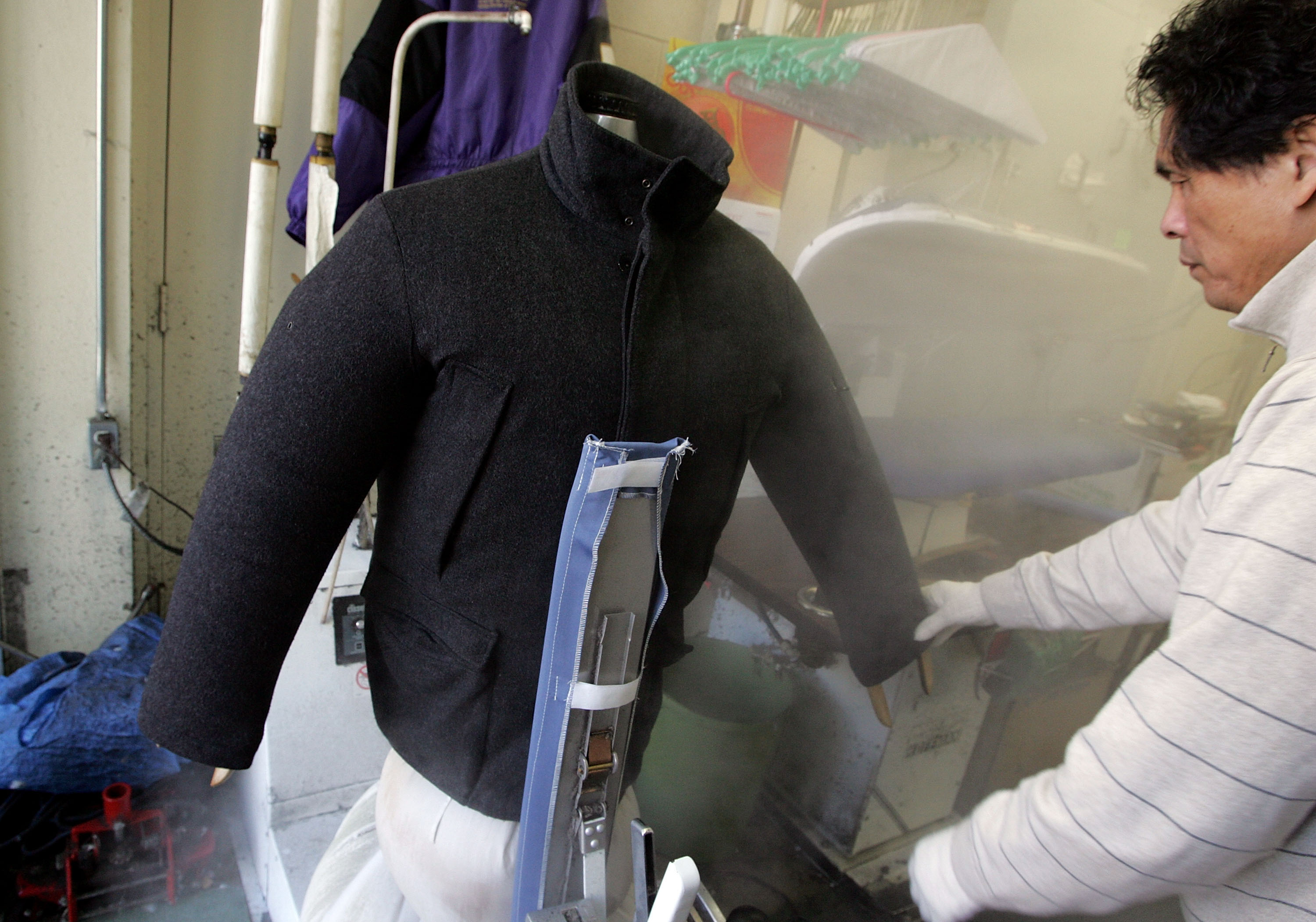 A worker at a dry cleaner in San Francisco steams a wool coat | Source: Getty Images