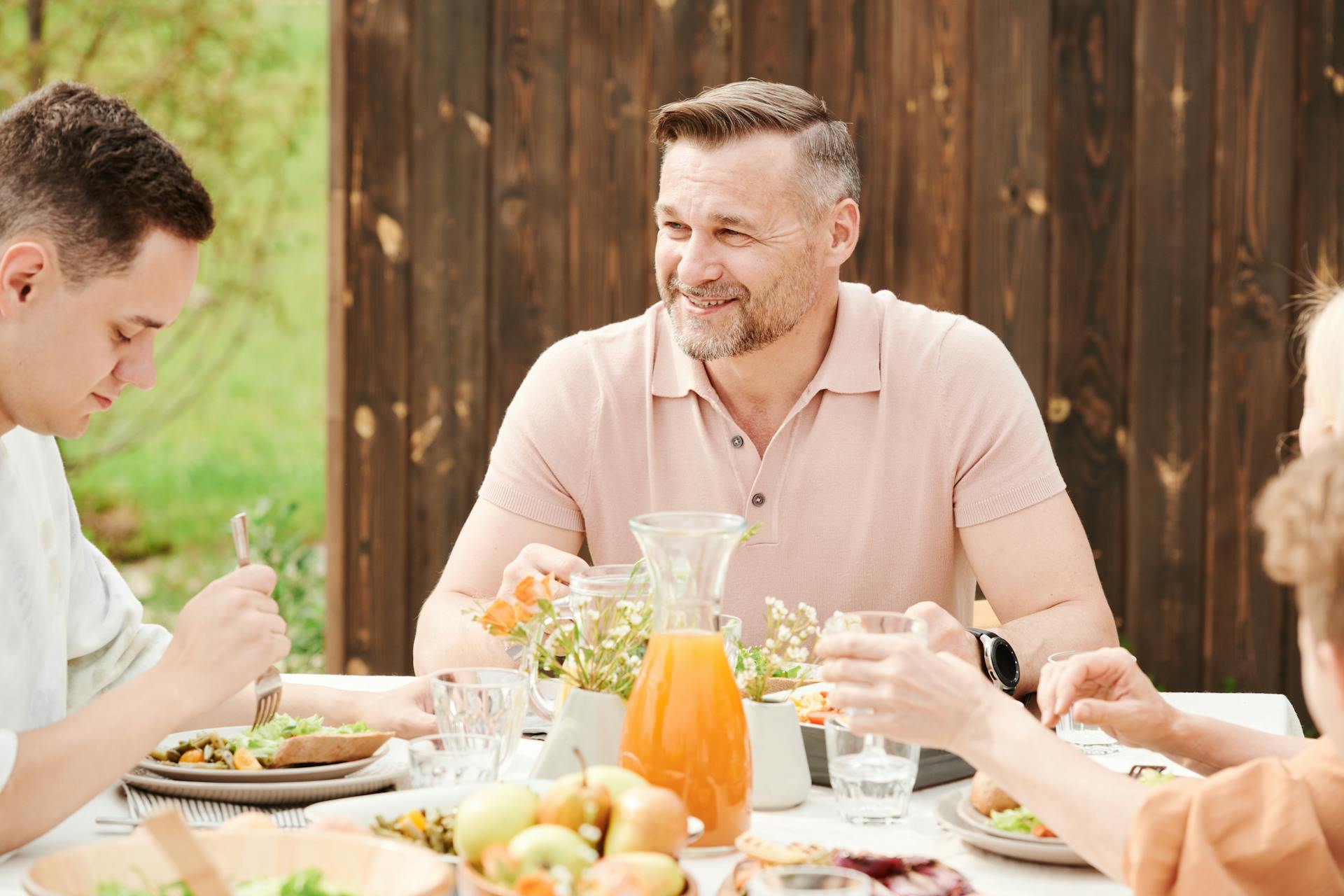 A smiling man at the dinner table with his family | Source: Pexels