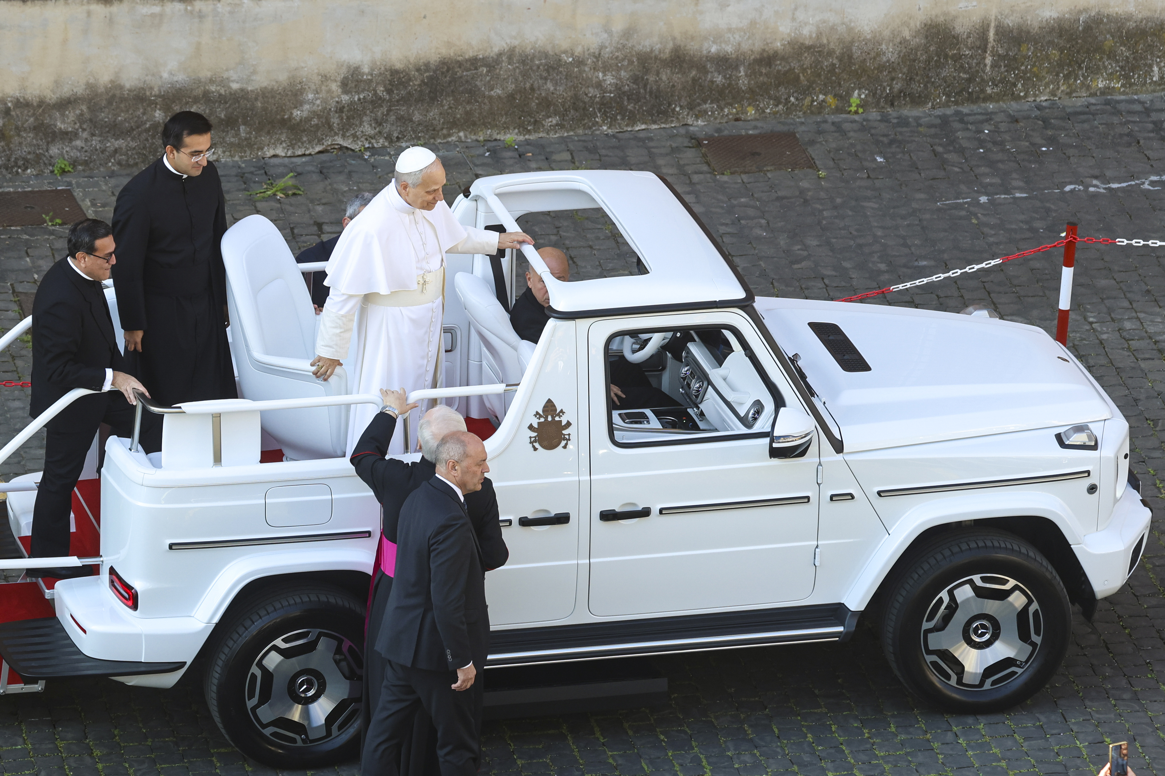 Pope Leo XIV climbs into the Popemobile ahead of his inauguration Mass in St. Peter's Square on May 18, 2025, as aides and clergy stand nearby. | Source: Getty Images