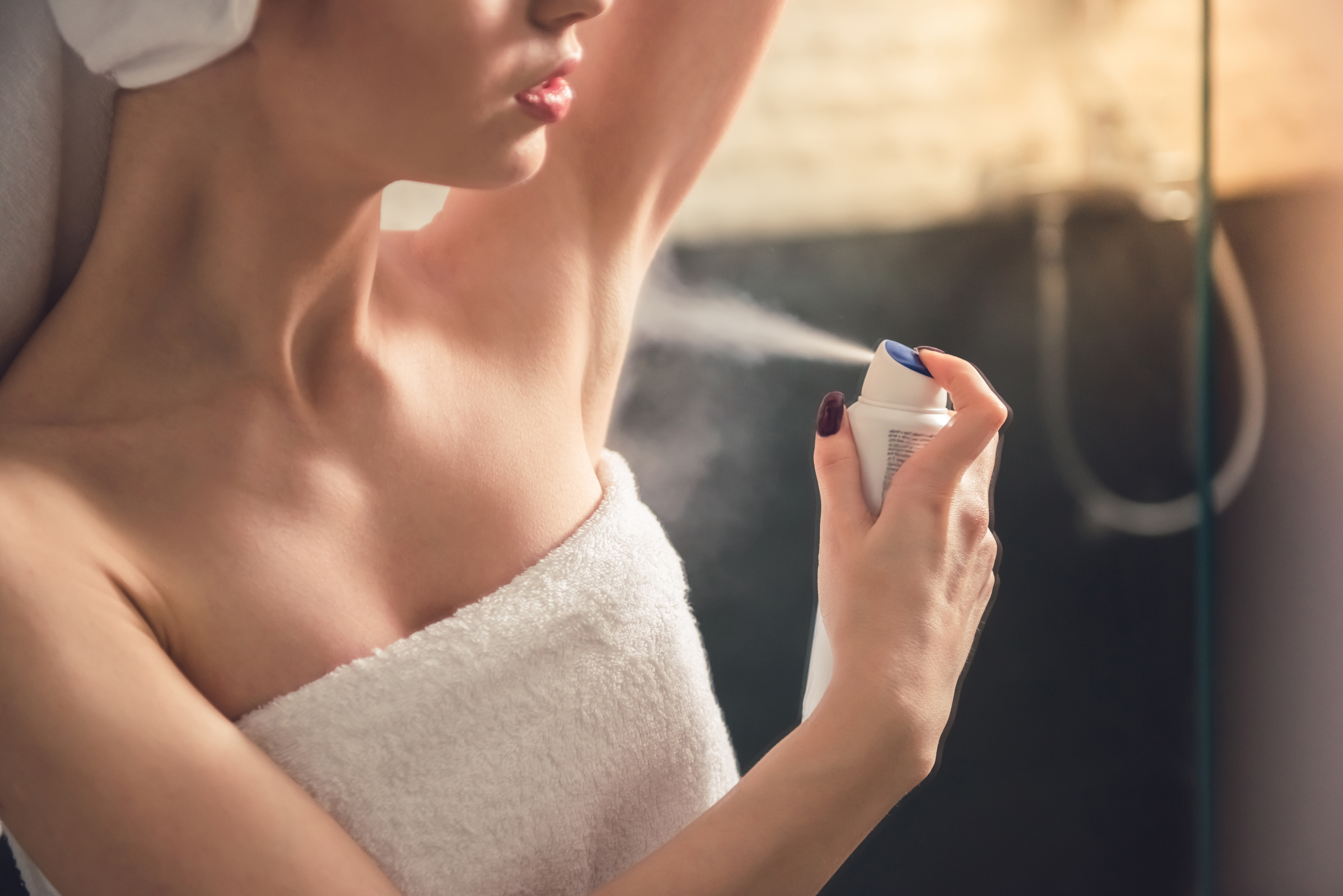 Woman spraying deodorant on her underarms | Source: Shutterstock