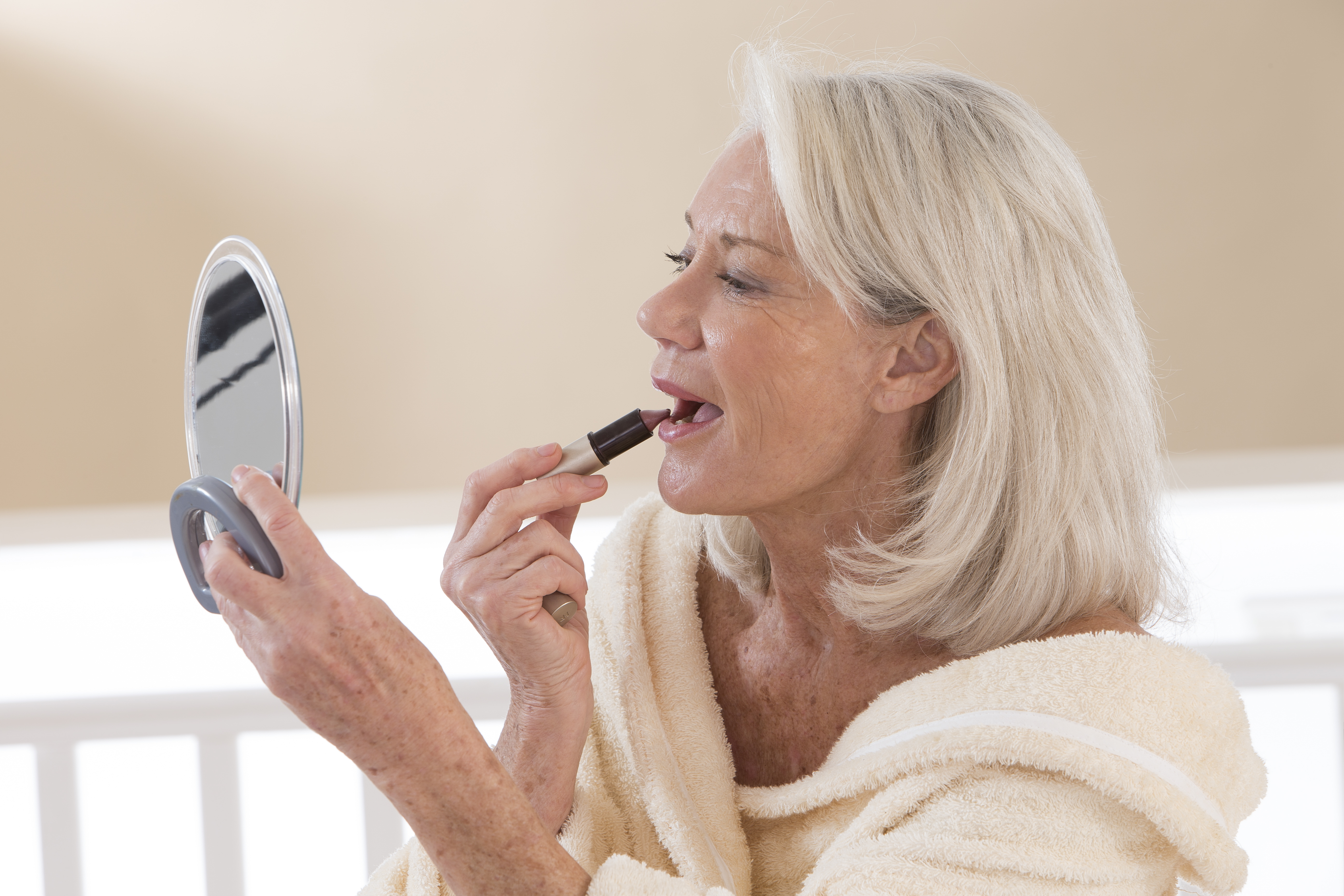 A senior woman applying lipstick | Source: Shutterstock