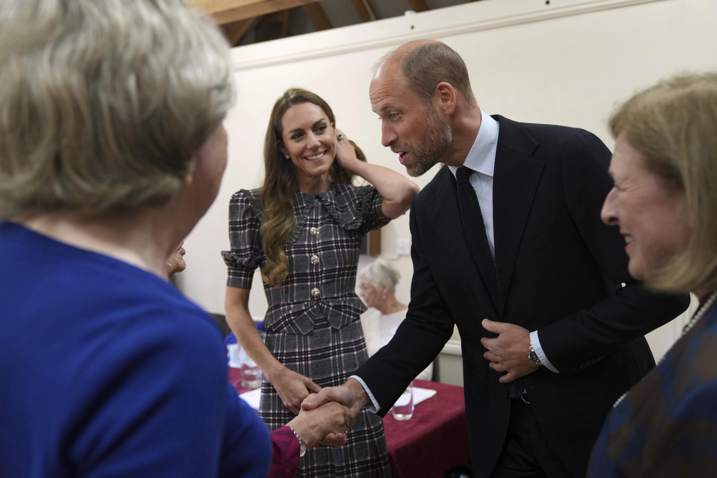 Princess Catherine smiling at Prince William, as he shakes hands with people. | Source: Getty Images