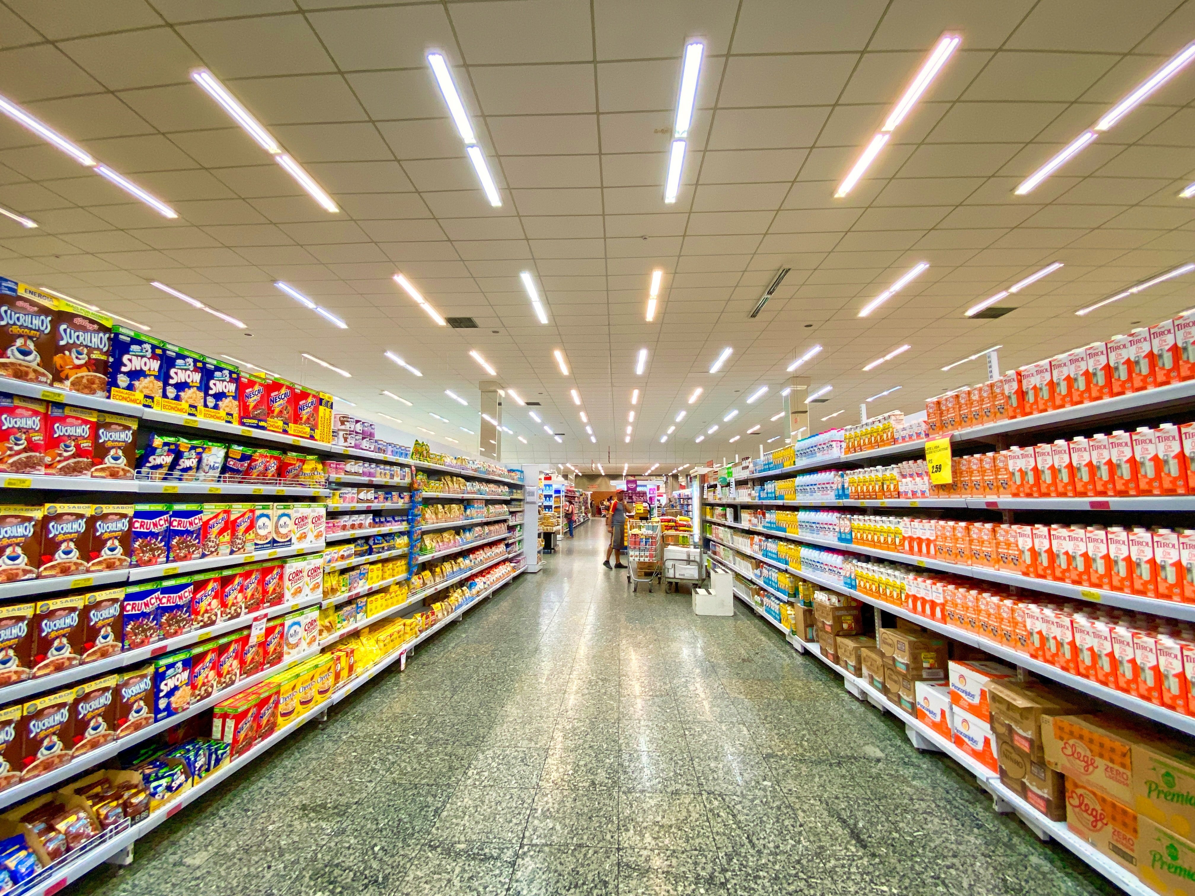 Food aisles and customer can be seen inside of a grocery store | Photo: Unsplash/Nathália Rosa