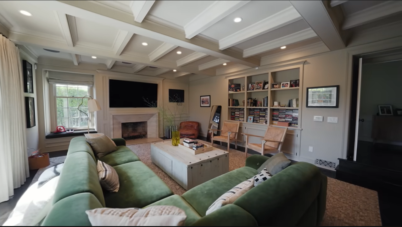 The complete view of Palmer's media room showcases a beautiful coffered ceiling, a sleek fireplace, and walls lined with family entertainment. | Source: YouTube/@Archdigest