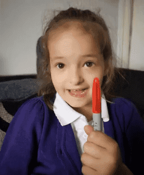 Lily Schooley holding the red permanent marker she used to draw dots on herself. | Source: YouTube/ jane choem