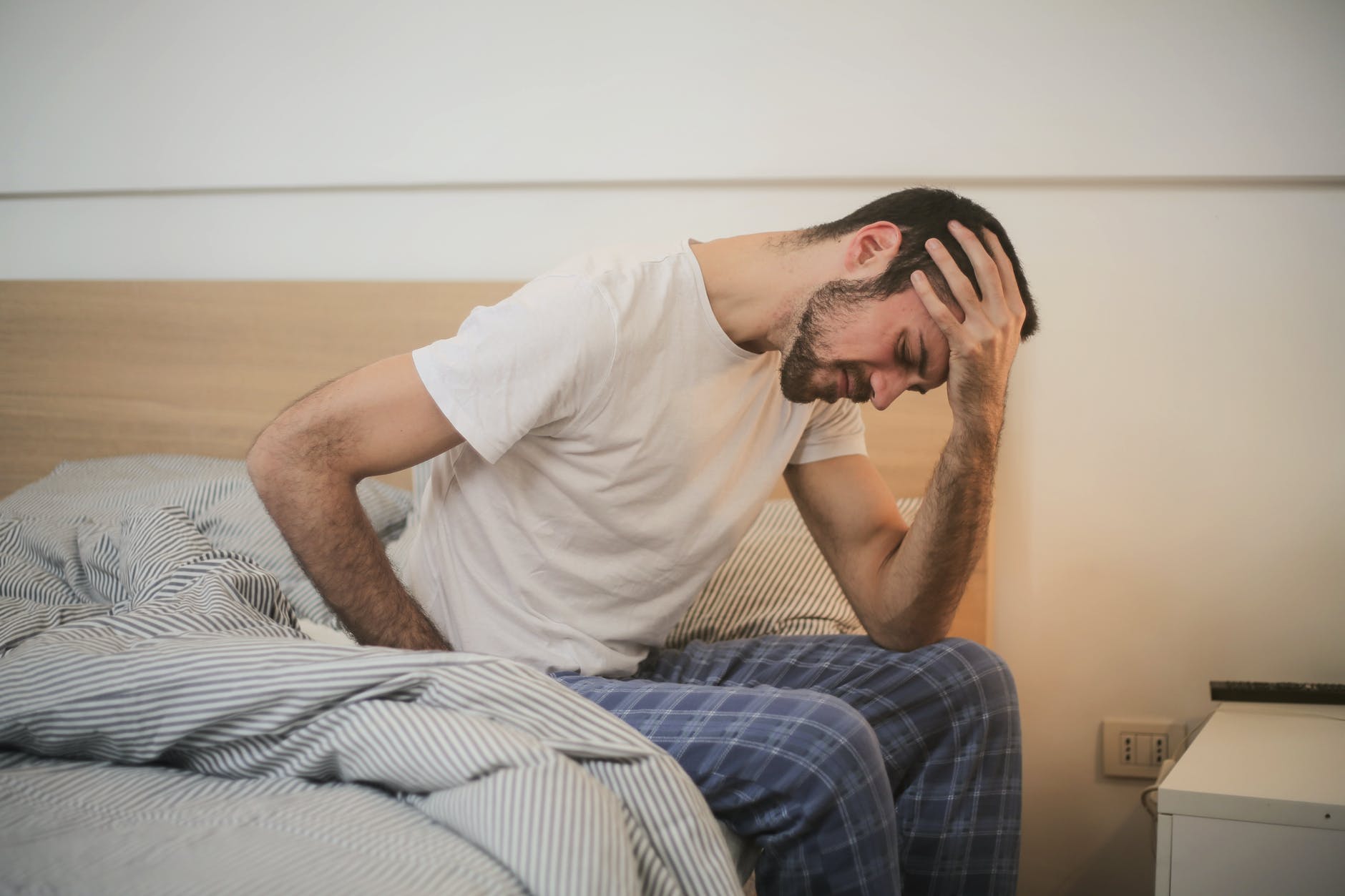 Hombre se sienta a la orilla de su cama muy preocupado. | Foto: Pexels