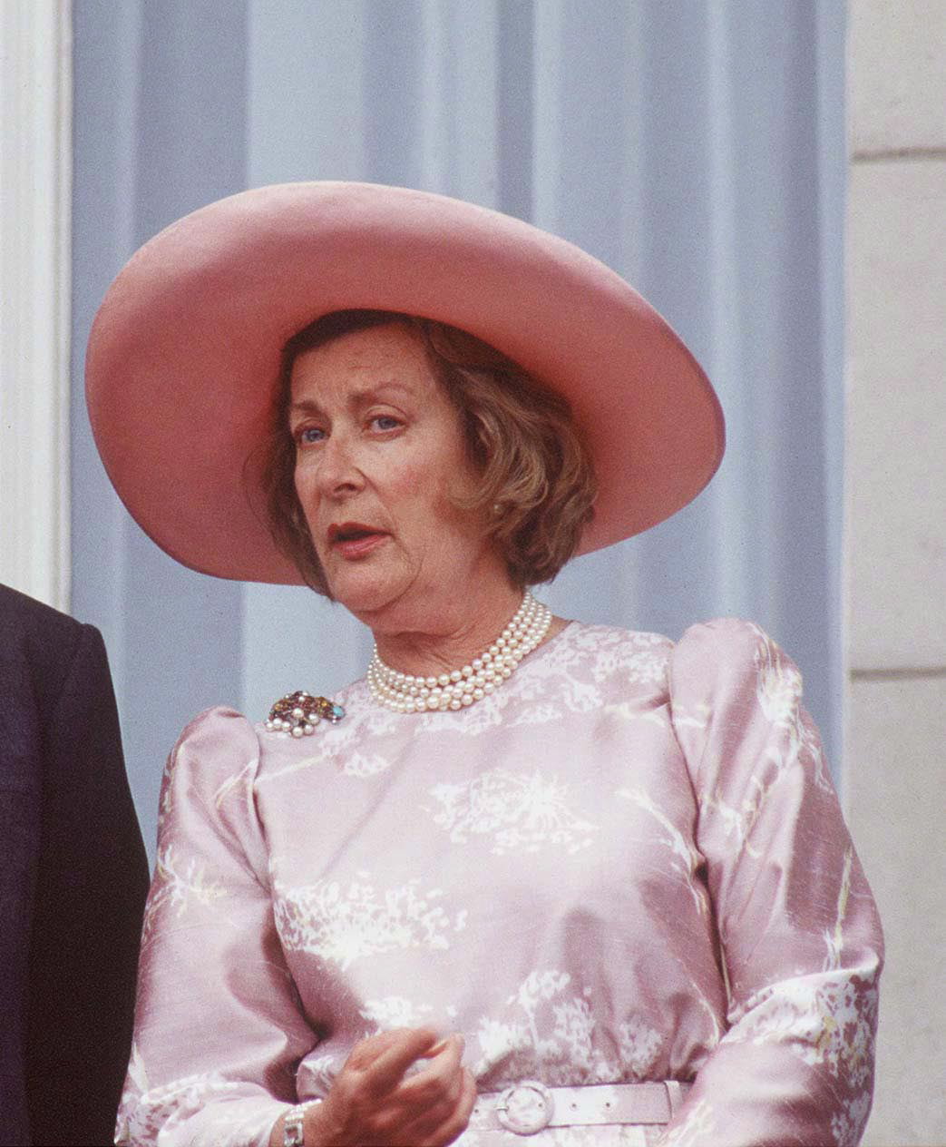 Taken on 14 June 1993 at Buckingham Palace, Lady Pamela Hicks is pictured following Trooping the Colour, dressed in a pale ensemble with a wide-brimmed hat and pearl necklace, reflecting her enduring elegance during a formal royal occasion in London among fellow attendees.