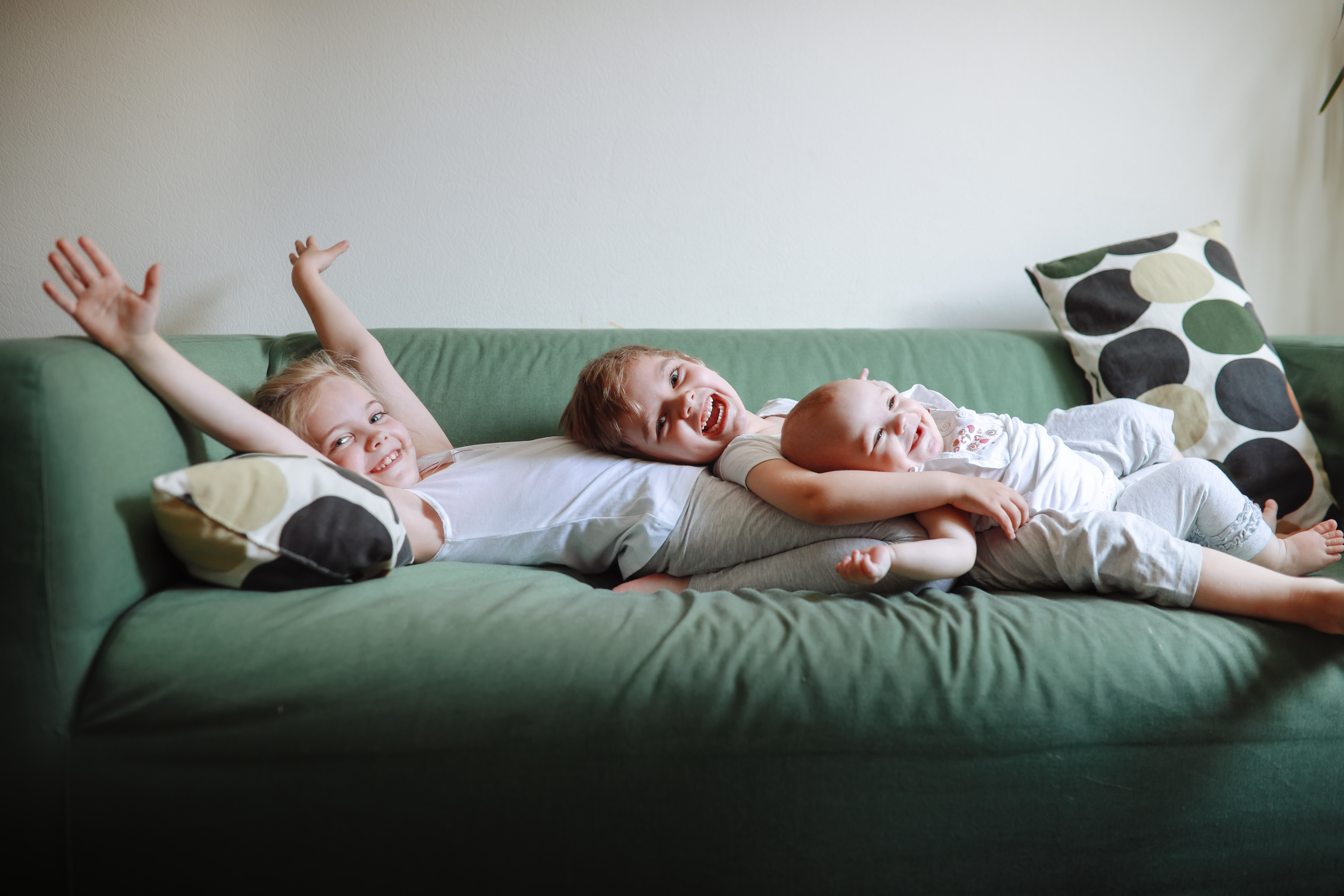 Three happy siblings lying on a sofa | Source: Getty Images
