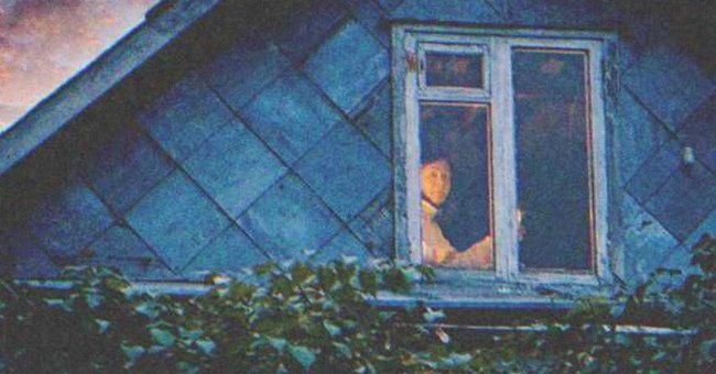 Una mujer pálida observando desde la ventana de una casa. | Foto: Shutterstock